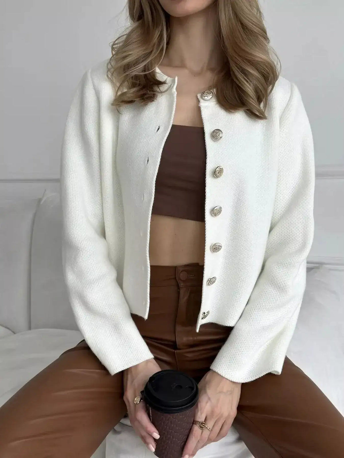 White crew neck button down cardigan by Evie's Dreamland paired with a brown crop top and faux leather pants.