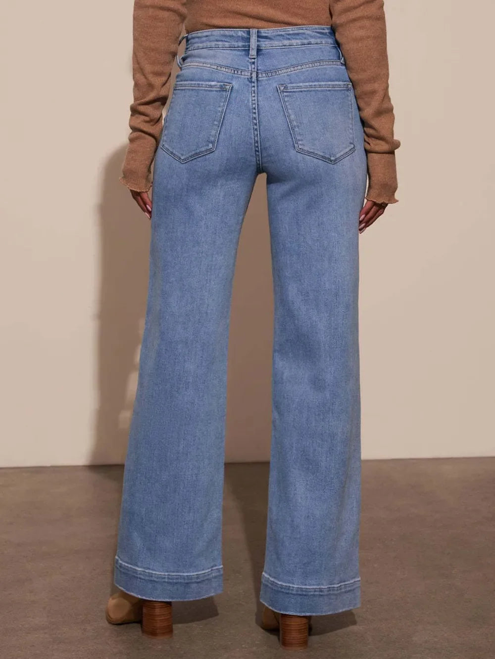 Woman wearing high-waisted wide leg light blue jeans and brown boots