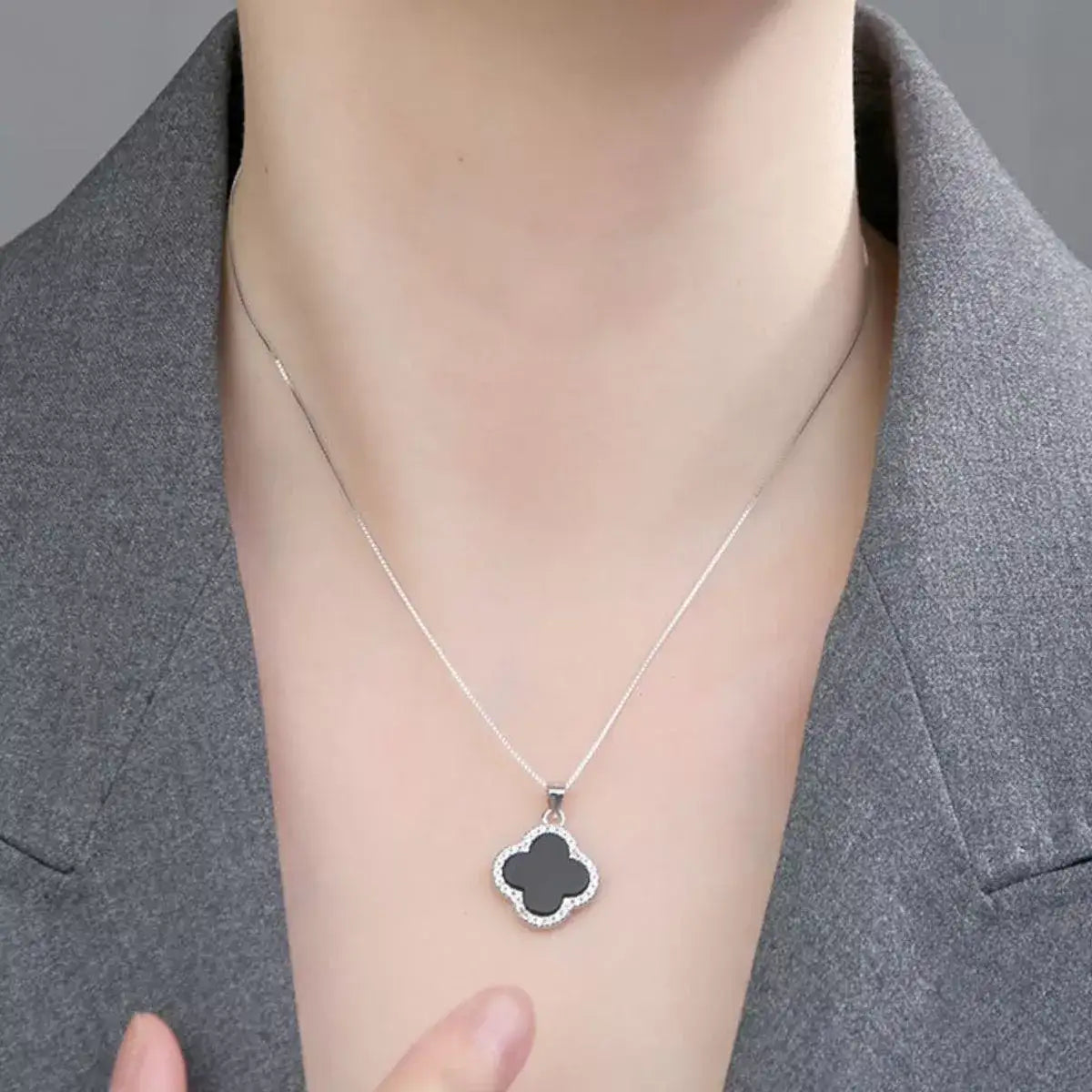 Woman wearing an Evie's Dreamland sterling silver necklace with a black clover pendant.
