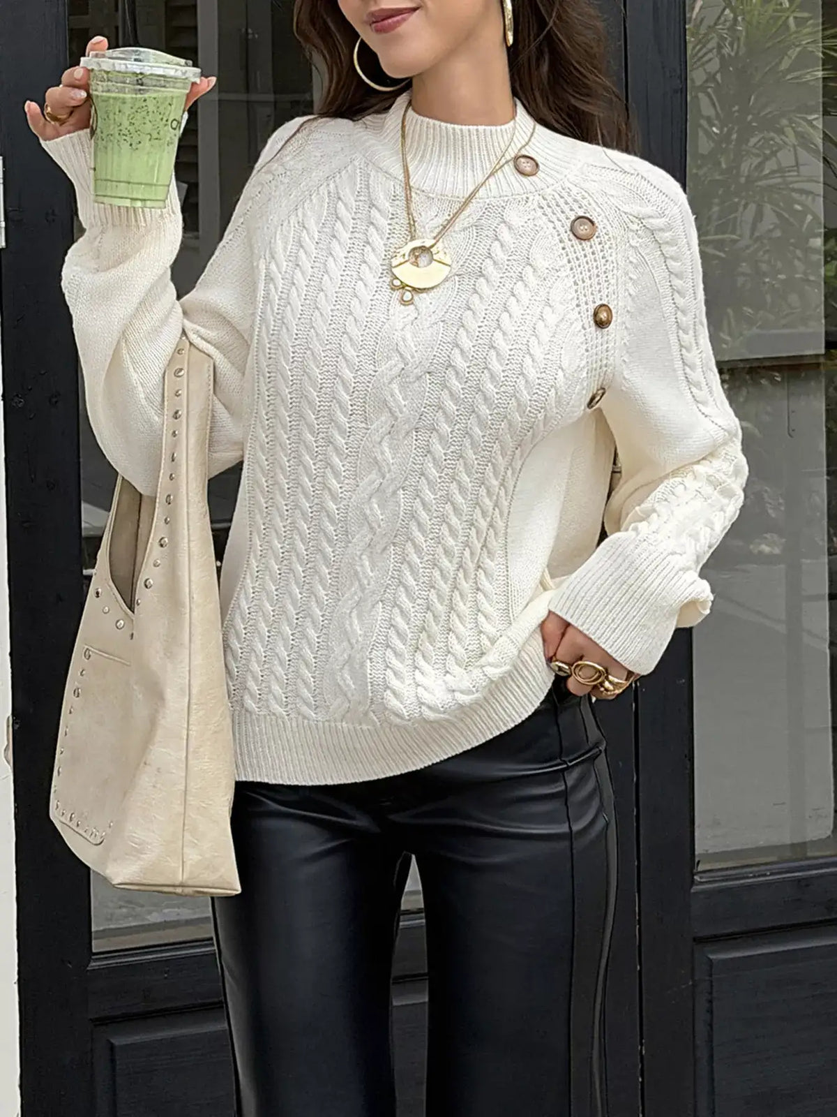 Woman wearing a white mock neck cable-knit sweater by Evie's Dreamland with black leather pants.