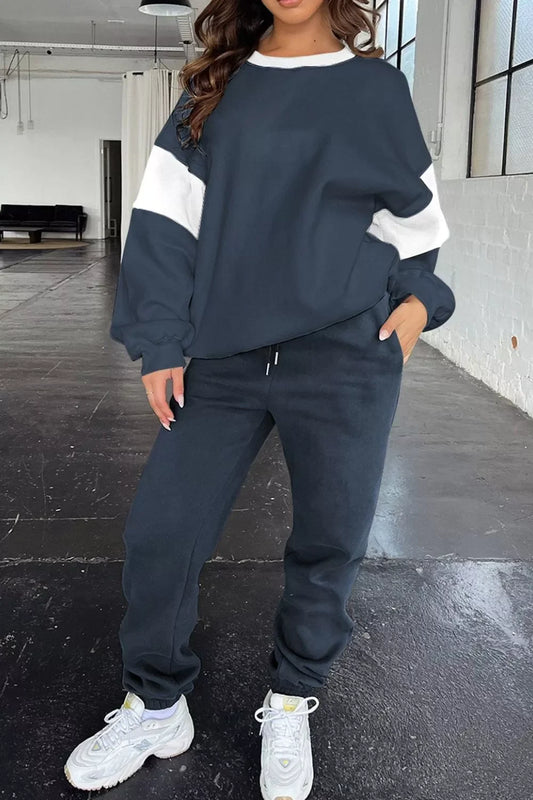 Woman wearing navy blue and white colorblock sweatshirt and matching joggers with white sneakers indoors