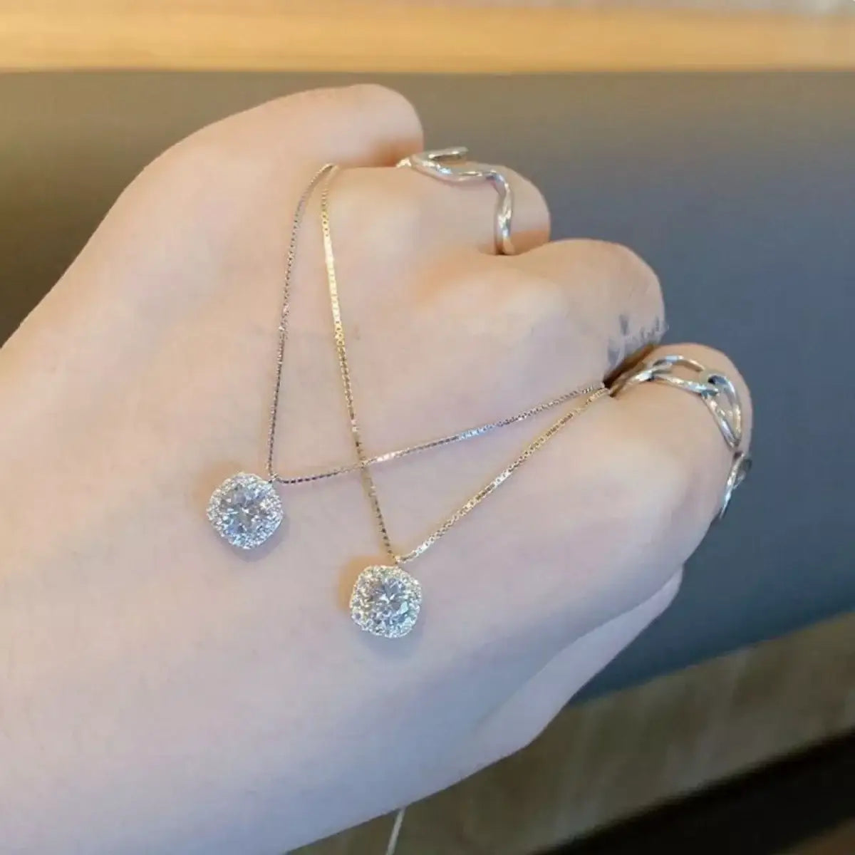 Two Evie's Dreamland 925 sterling silver zircon pendant necklaces and rings on a hand.