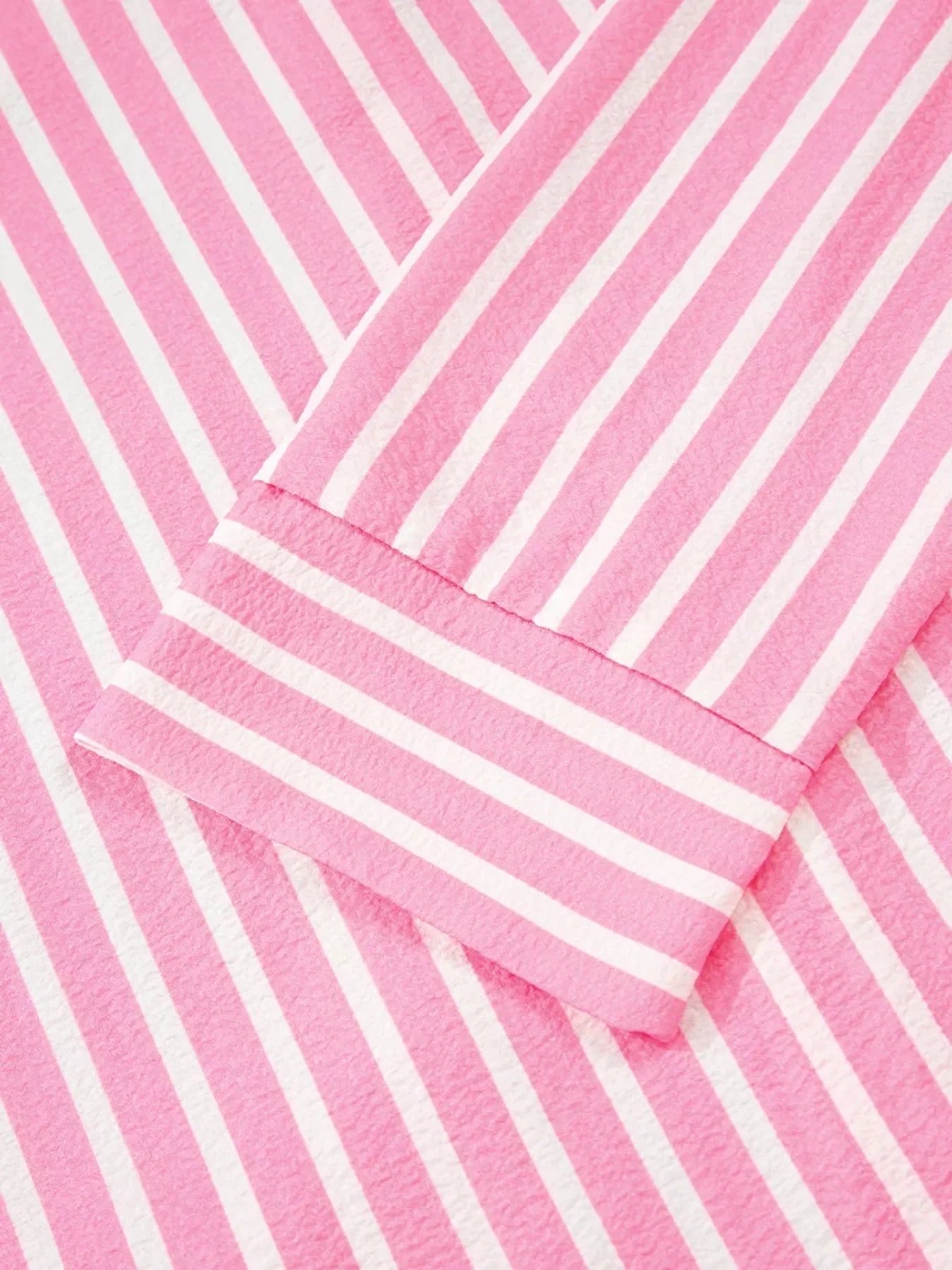 Close-up of pink and white striped fabric with textured pattern and visible seam