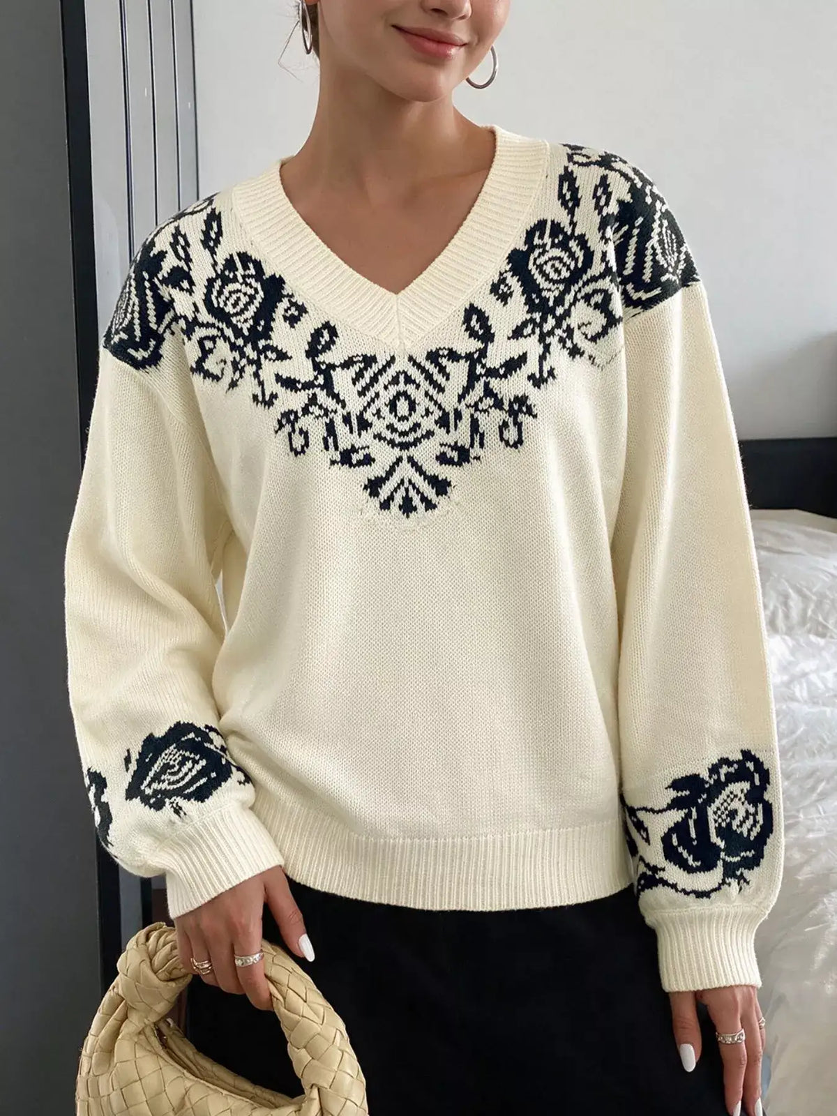 Woman wearing an Evie's Dreamland cream v-neck sweater with navy floral patterns and dropped shoulders.