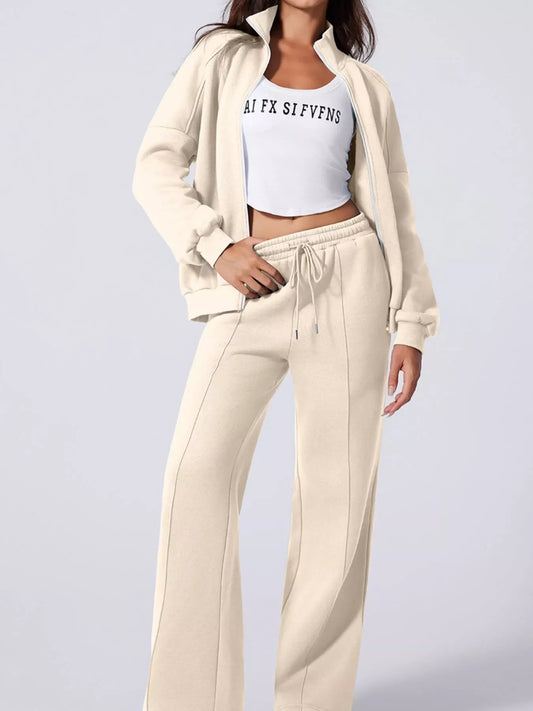 Woman wearing beige zip-up jacket and matching wide-leg sweatpants with white crop top
