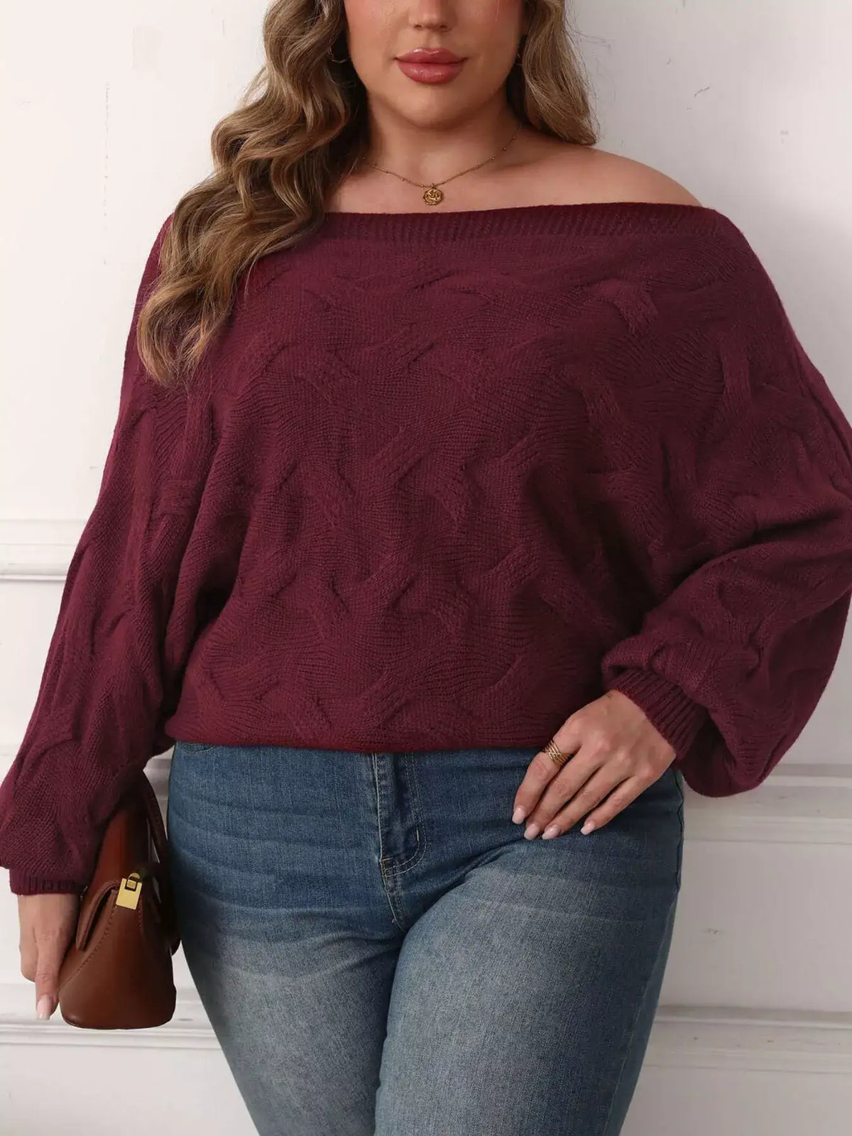Plus size burgundy off-shoulder long sleeve sweater by Evie's Dreamland paired with blue jeans.