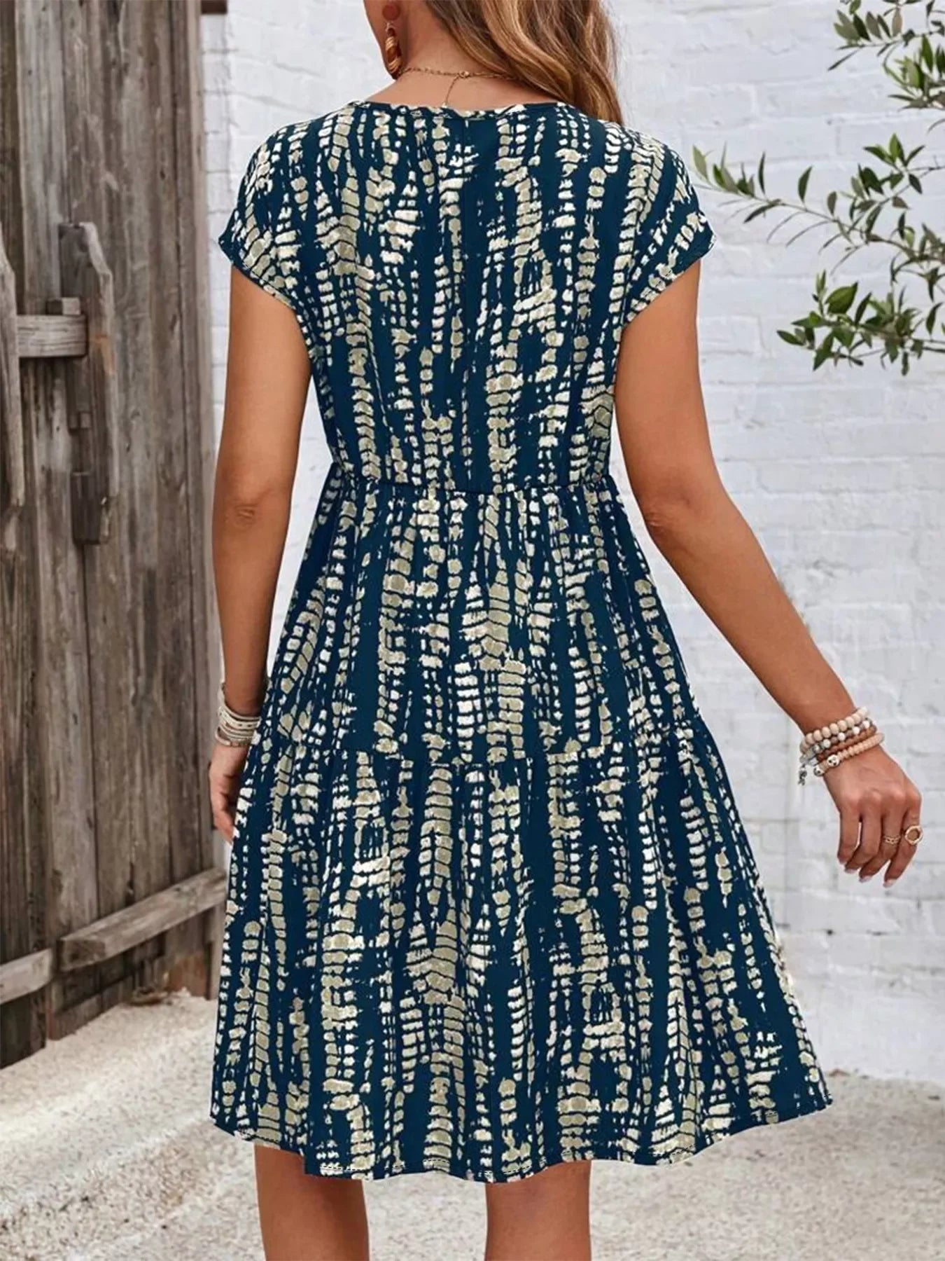 Back view of woman wearing navy blue and beige patterned short sleeve casual dress outdoors