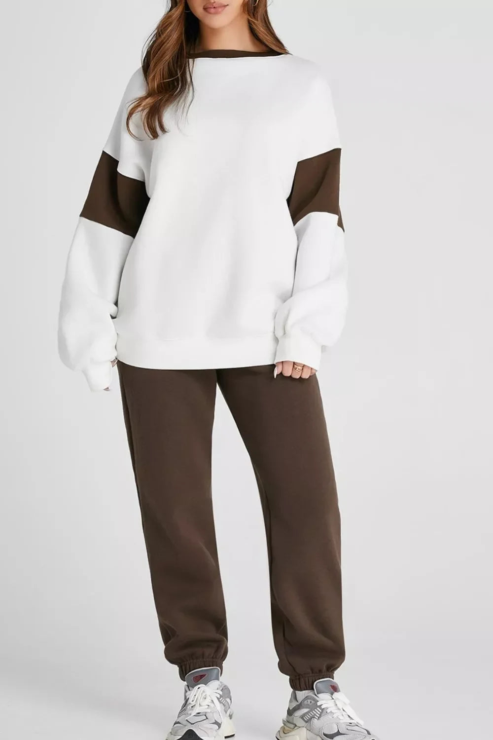 Woman wearing a white and brown color-block oversized sweatshirt with matching brown jogger pants and sneakers