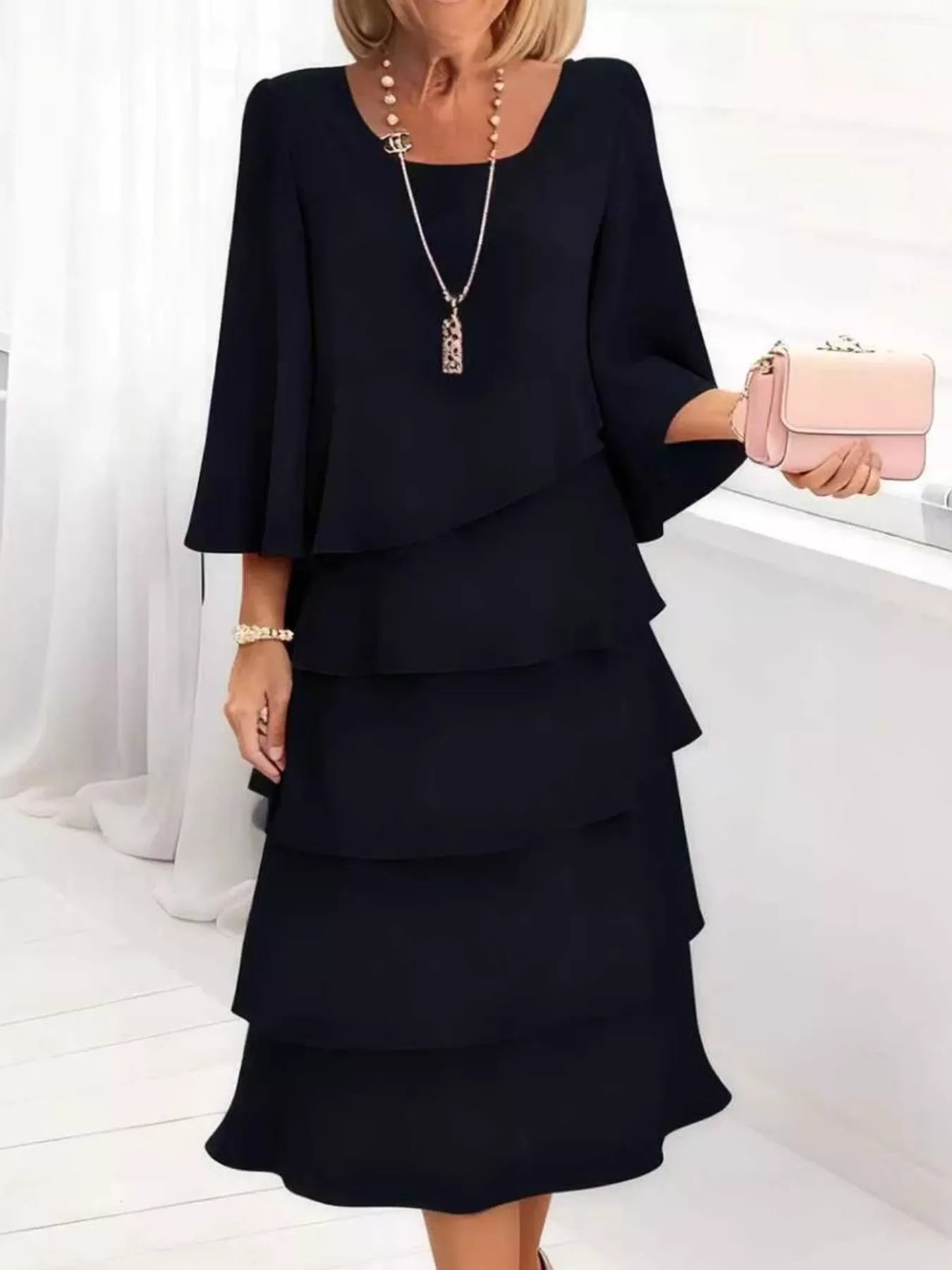 Elegant black tiered midi dress with bell sleeves, paired with pearl necklace and pink clutch for chic everyday style