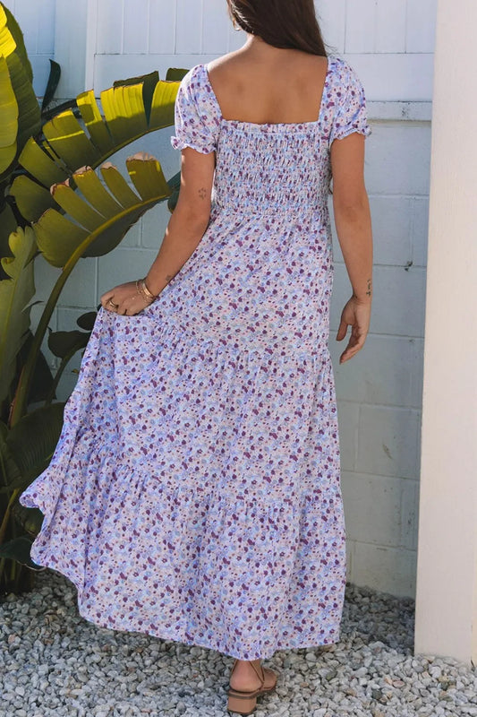 Woman in a floral maxi dress with puff sleeves standing outdoors by green plants