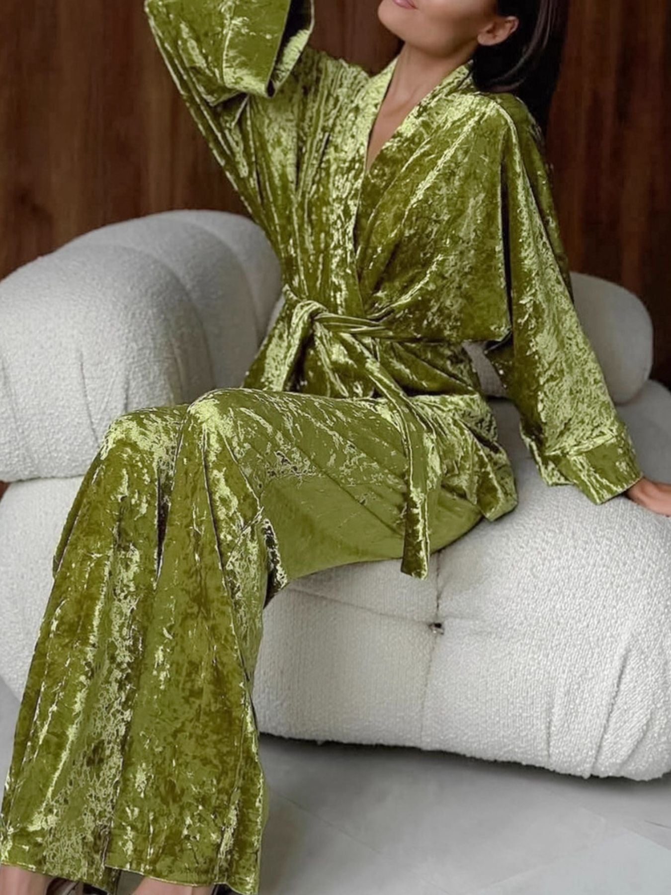 Woman lounging in a green velvet loungewear set on a modern white chair