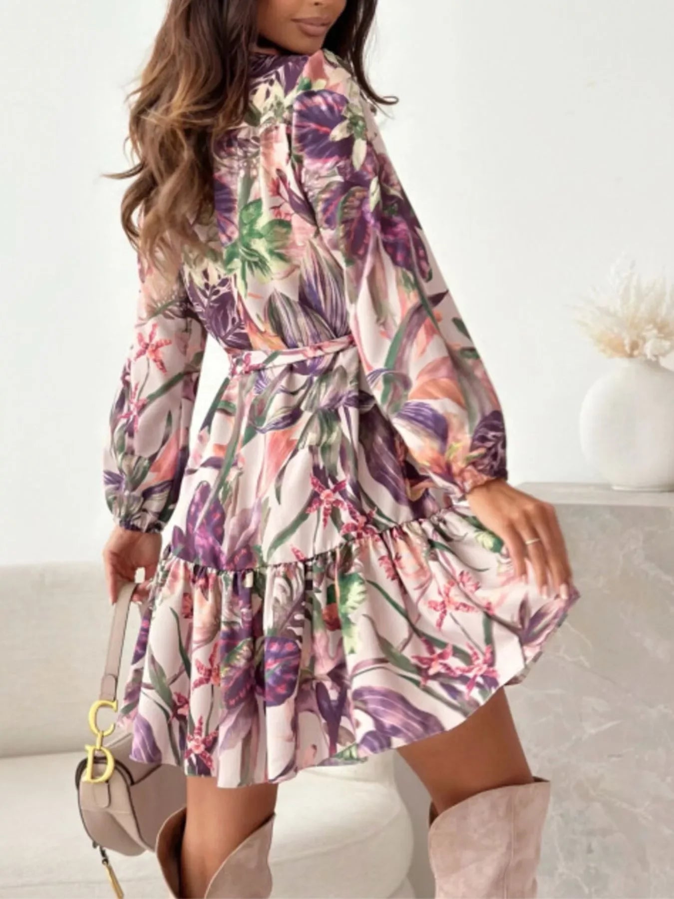 Floral print dress with long sleeves, ruffled hem, and tie waist, paired with knee-high boots and a handbag