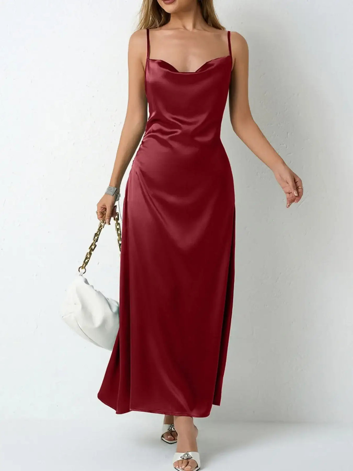 Woman wearing a burgundy satin cowl neck slip maxi dress from Evie's Dreamland with a white handbag.