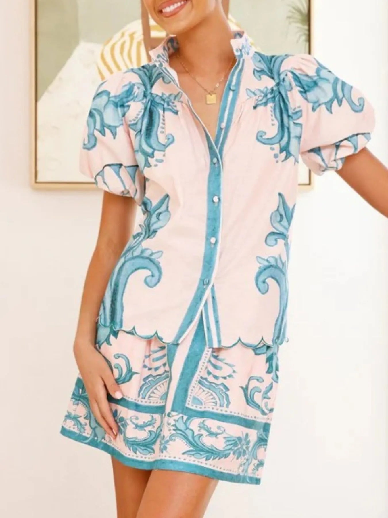 Woman wearing a pastel pink and teal floral print blouse and matching mini skirt set
