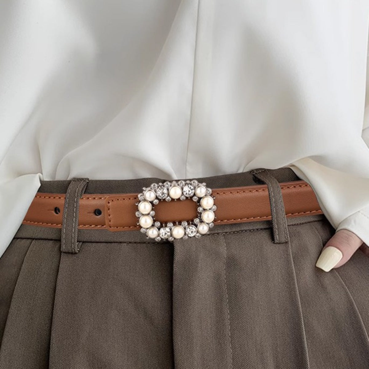 Brown leather belt with a pearl and rhinestone buckle worn over olive brown trousers
