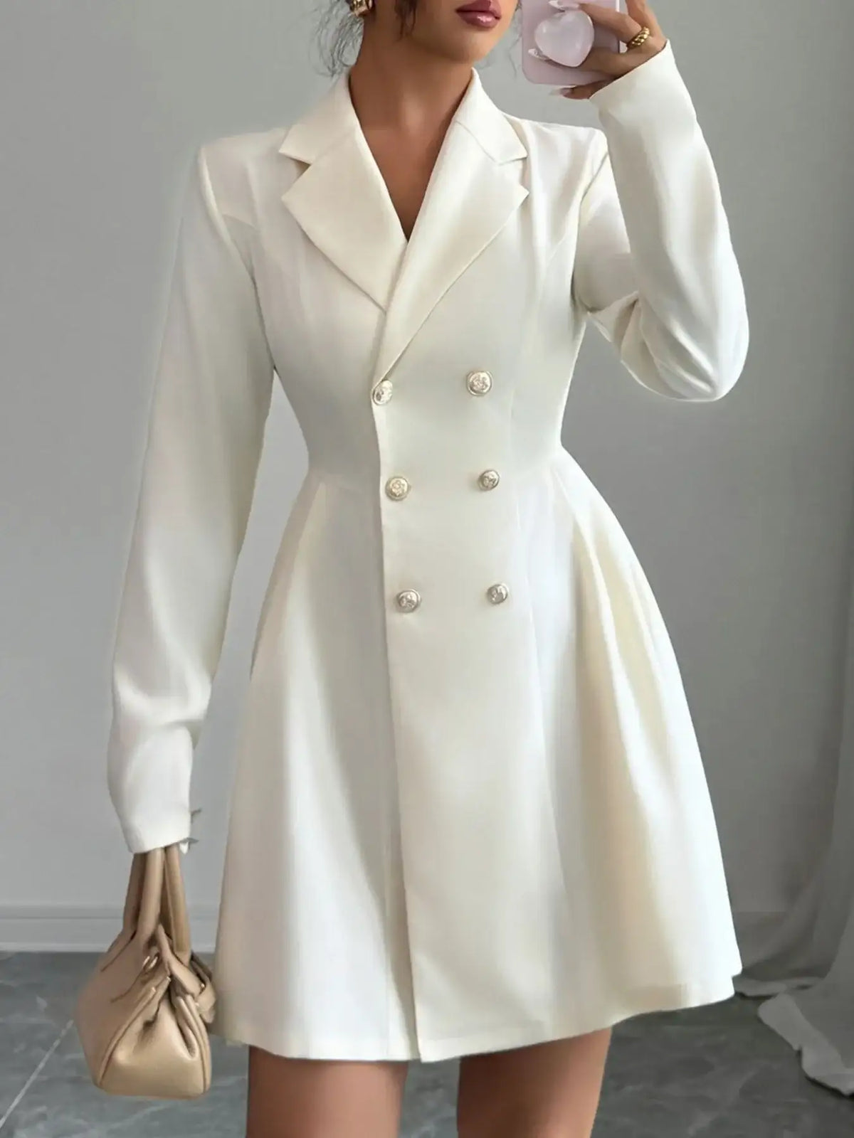 Woman wearing an Evie's Dreamland white double-breasted blazer dress with long sleeves and pleated skirt.
