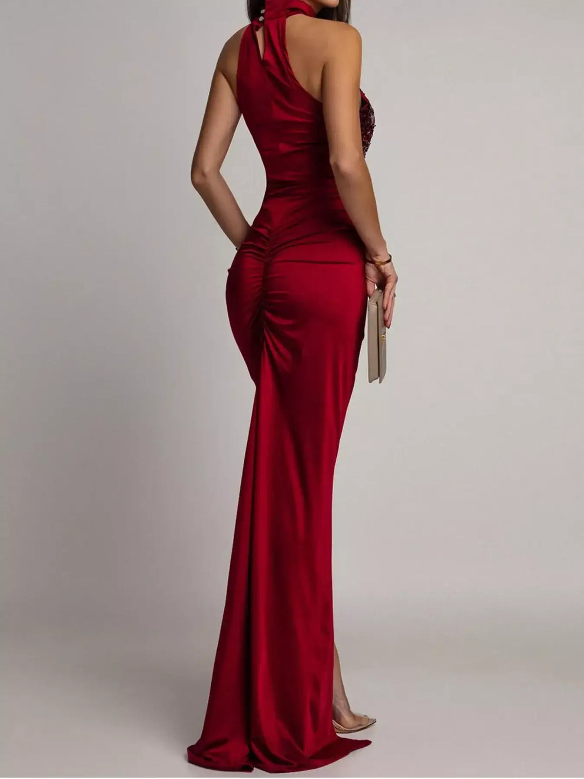 Back view of a red sleeveless maxi dress by Evie's Dreamland with ruched detailing and a halter neckline.