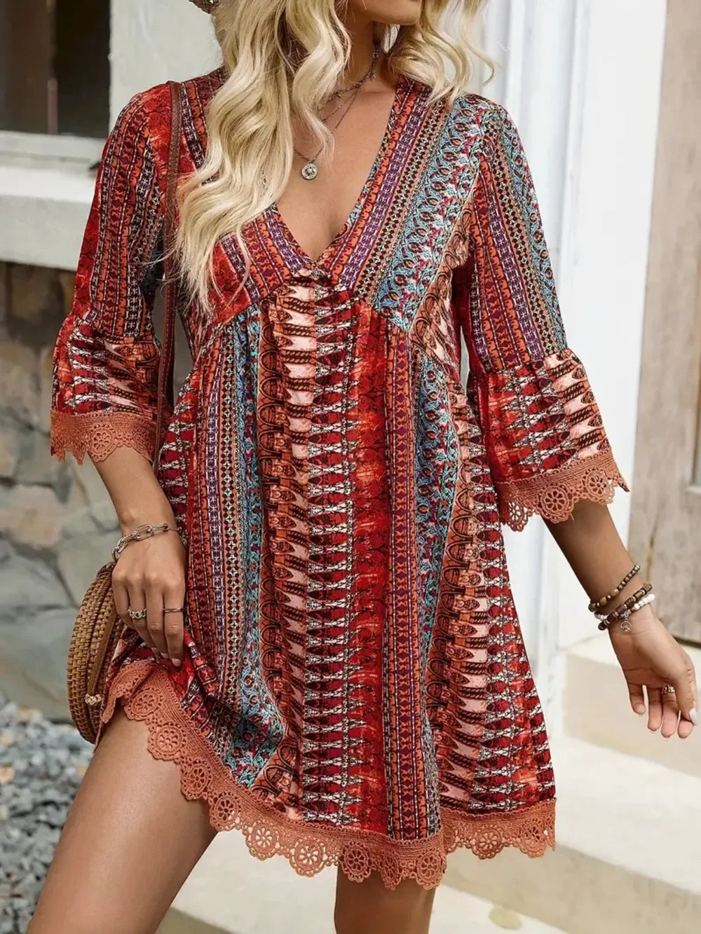 Woman wearing a boho patterned red and orange mini dress with crochet trim