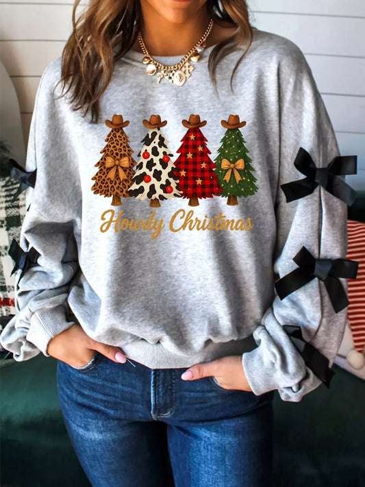Woman wearing grey Christmas sweatshirt with cowboy hat trees and Howdy Christmas text, black bows on sleeves