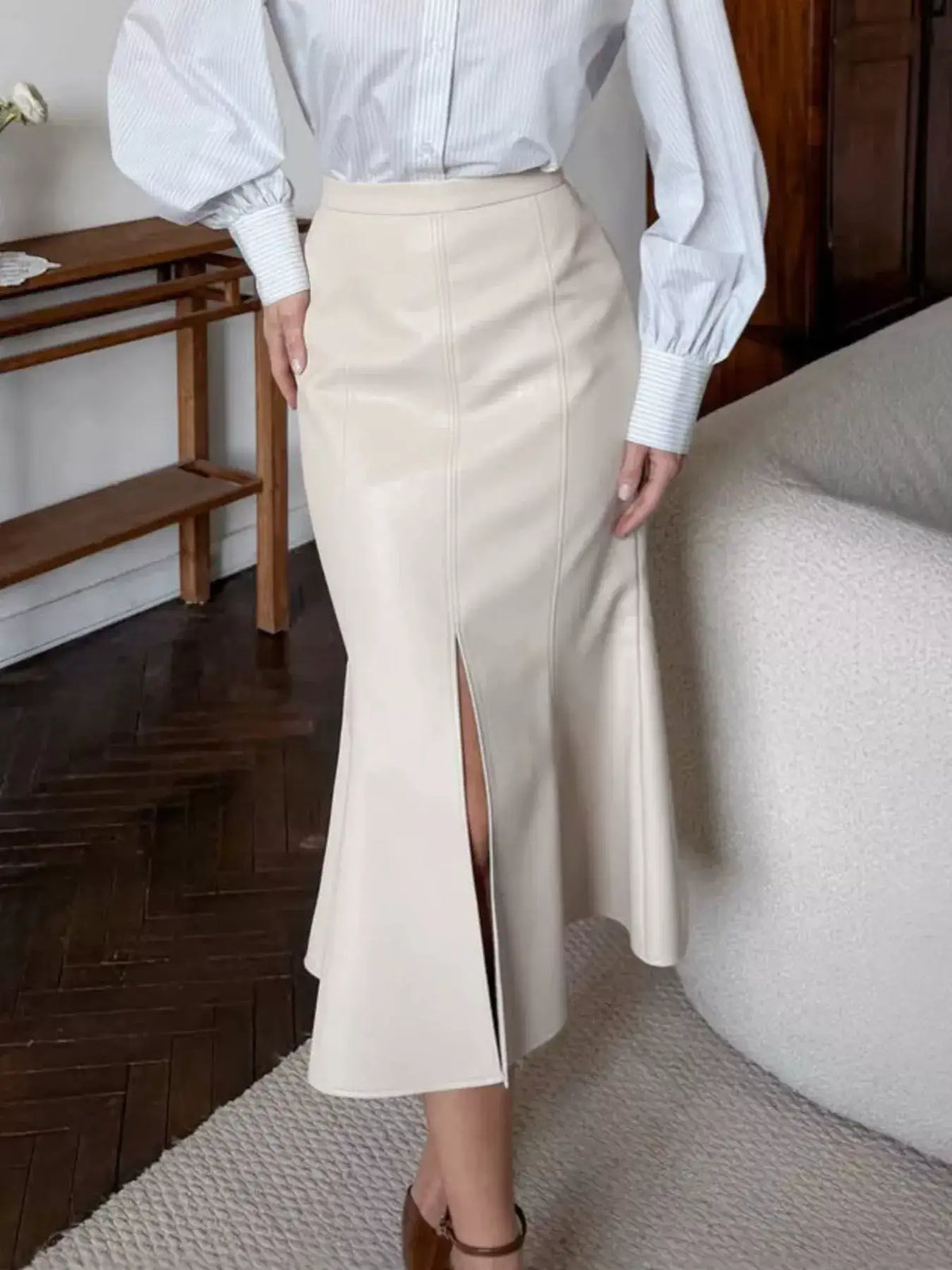 Evie's Dreamland cream faux leather mermaid midi skirt with a front slit, paired with a blue striped shirt.