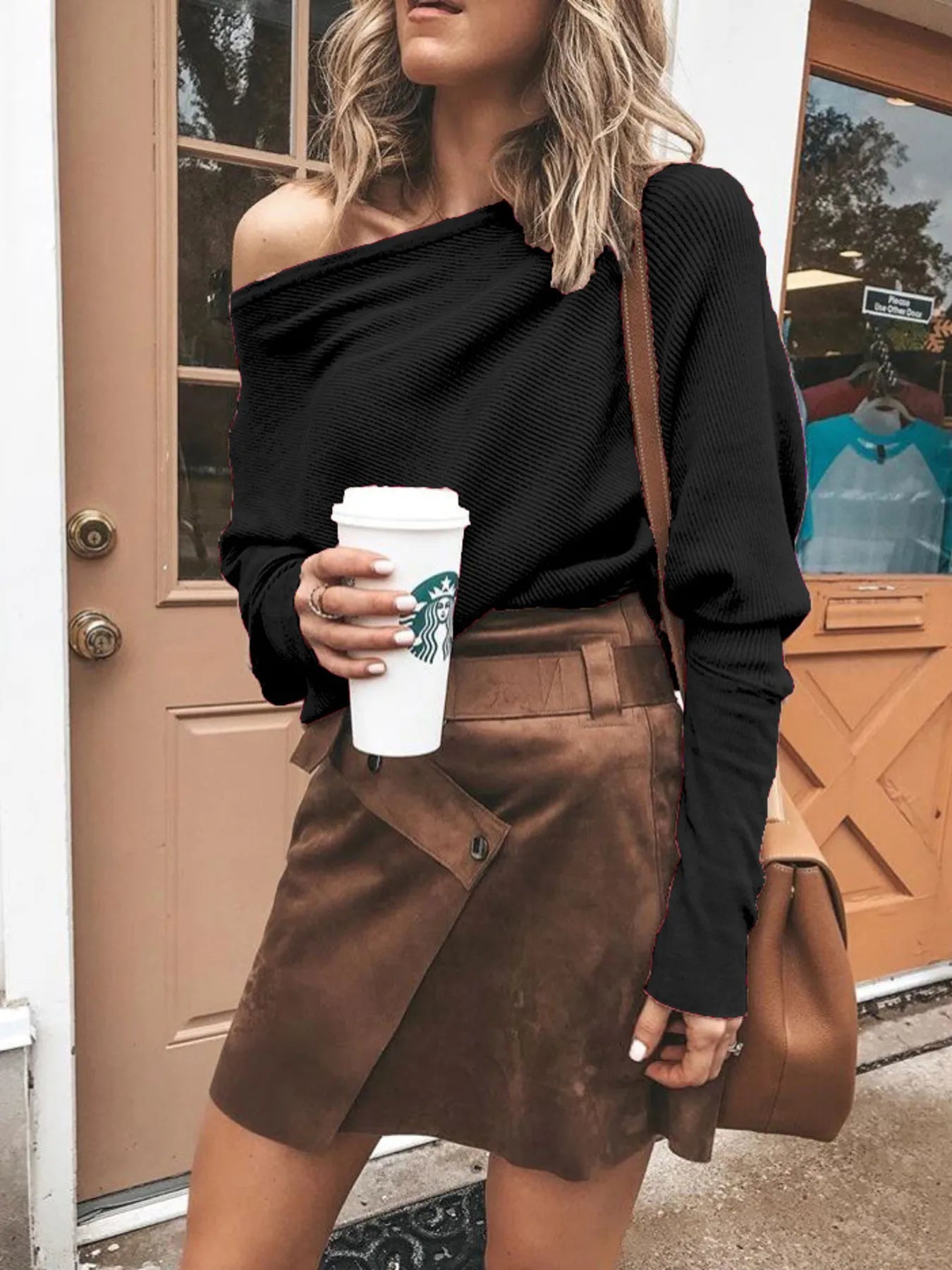 Woman in black off-shoulder top and brown suede skirt holding Starbucks coffee cup