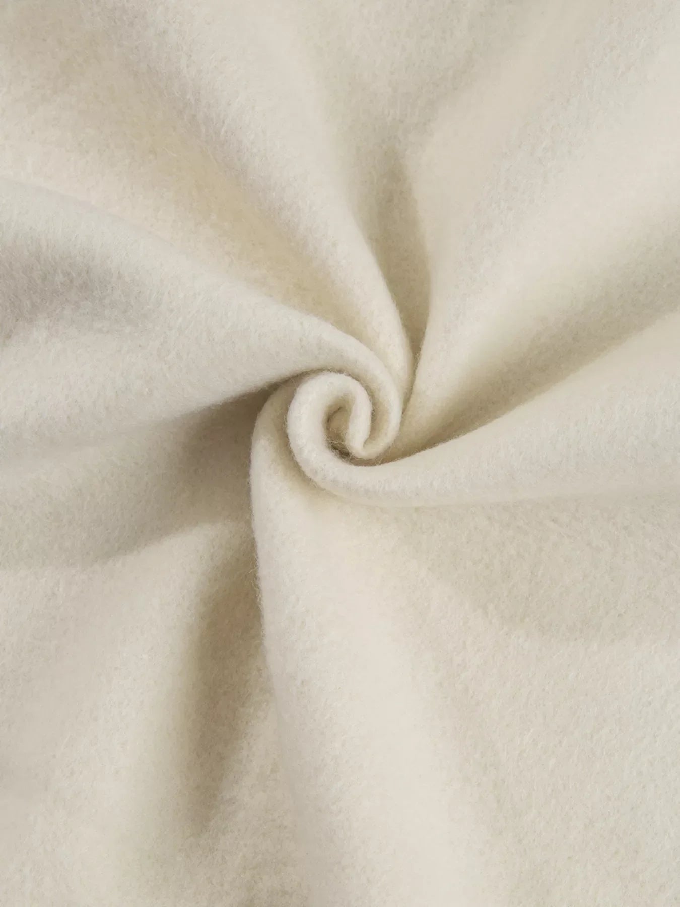 Close-up of soft cream-colored fabric twisted into a spiral, highlighting texture