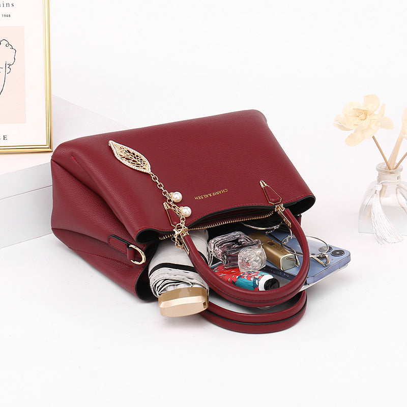 Red leather handbag with gold accents, open to show organized everyday essentials inside.
