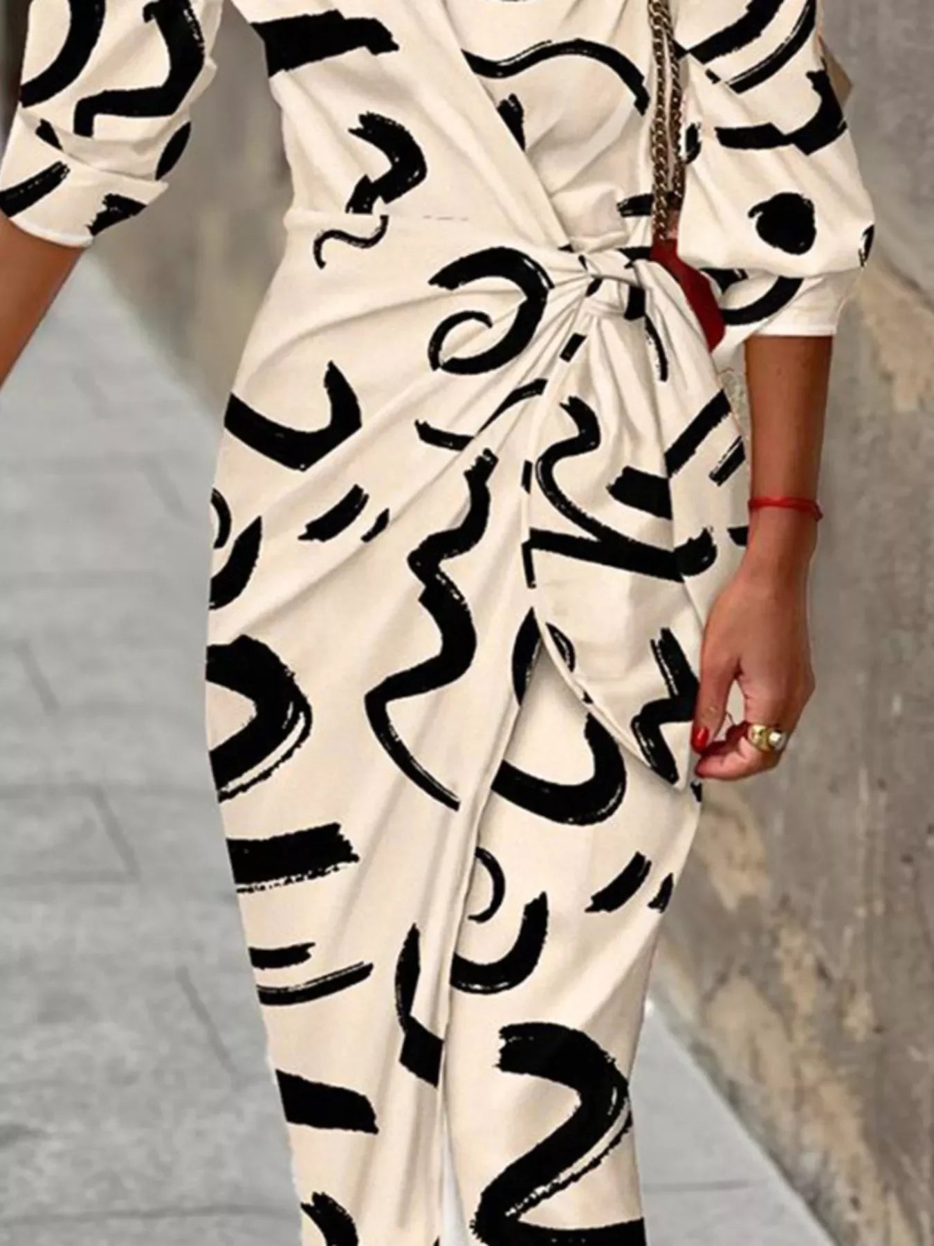 Close-up of white dress with abstract black brushstroke patterns and twist knot detail
