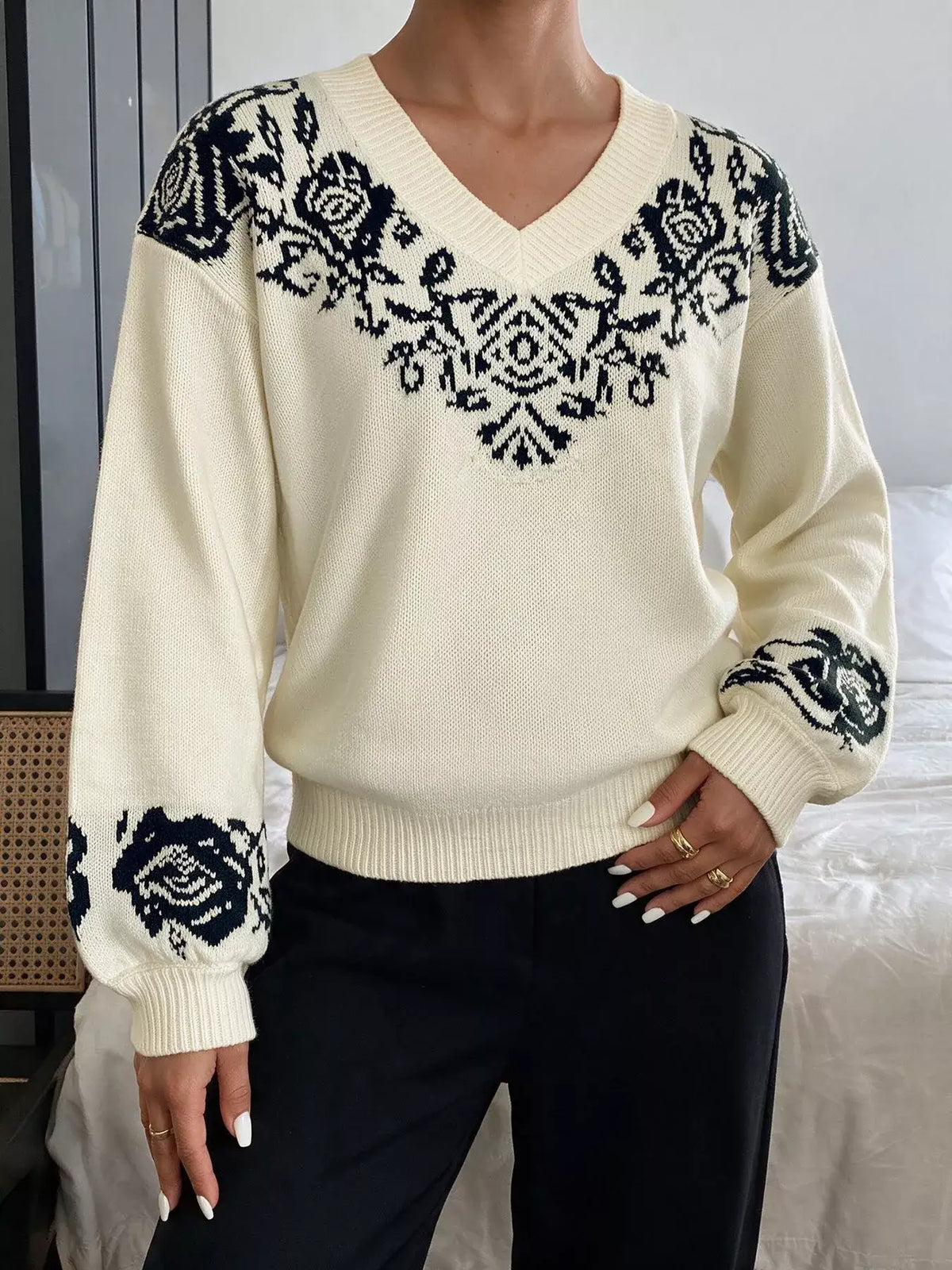 Cream Evie's Dreamland v-neck sweater with navy floral patterns on shoulders and cuffs, paired with black pants.