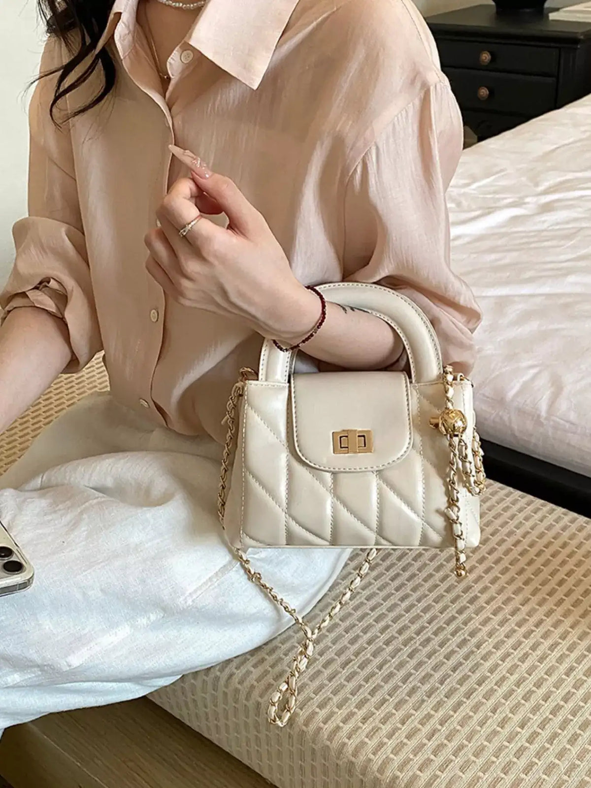 Woman holding a small cream quilted PU leather crossbody bag with gold chain strap by Evie's Dreamland.