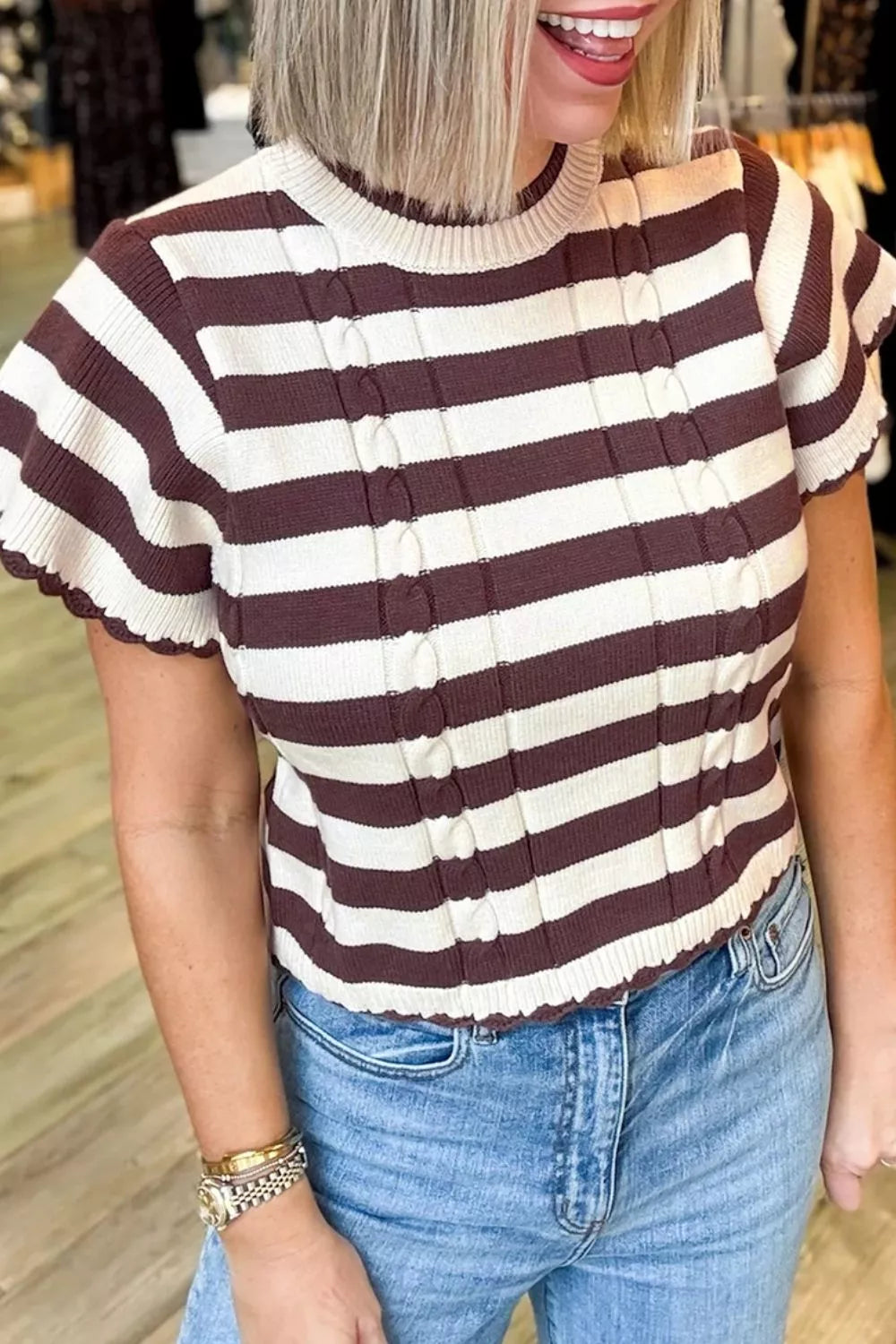 Woman wearing an Evie's Dreamland burgundy and cream striped cable-knit short sleeve sweater with blue jeans.
