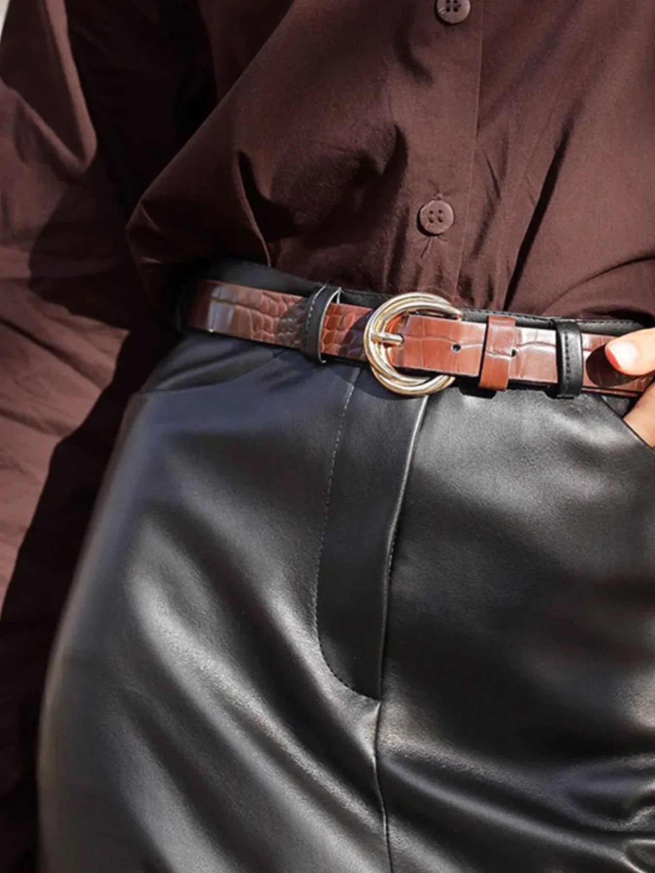 Brown faux crocodile belt with gold buckle on high-waisted black leather pants and brown shirt