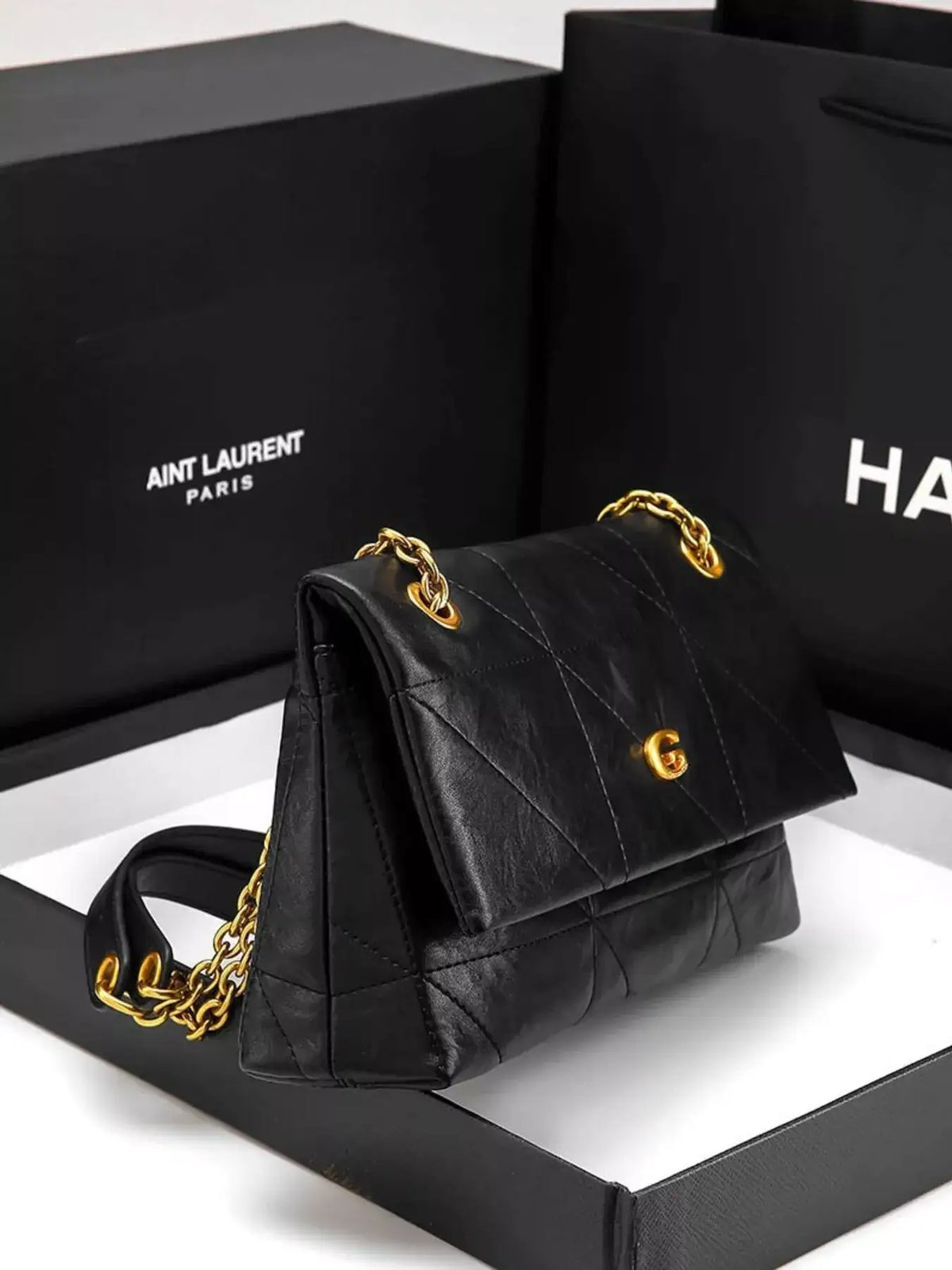 Black geometric quilted shoulder bag by Evie's Dreamland with a gold chain strap and gold logo clasp.