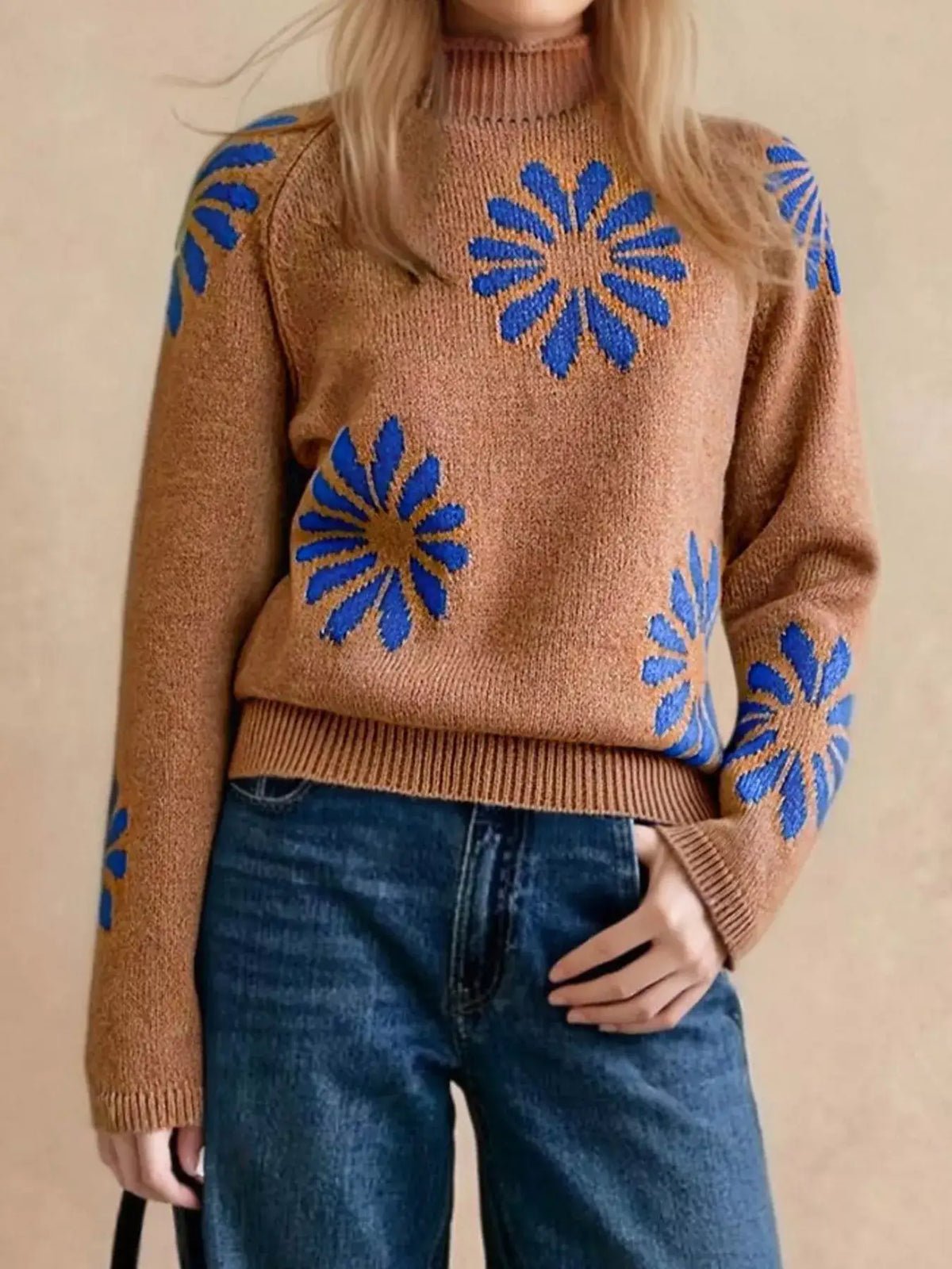 Woman wearing a brown Evie's Dreamland mock neck sweater with blue floral patterns and blue jeans.