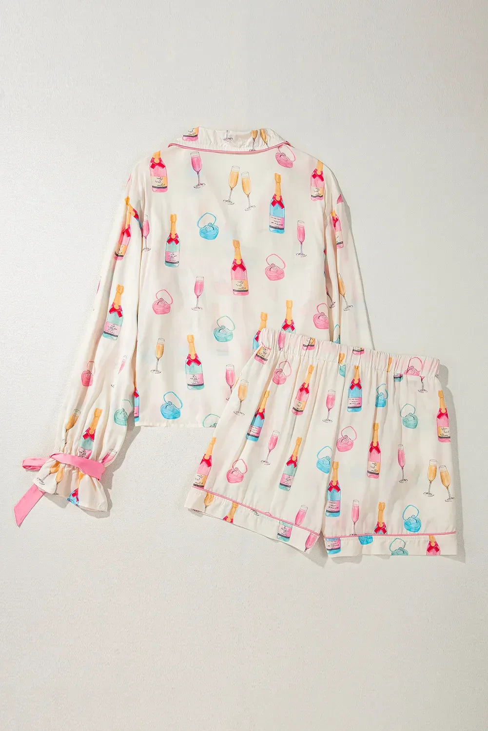 Cream pajama set with colorful champagne bottles, glasses, and perfume bottle prints, pink cuff ties