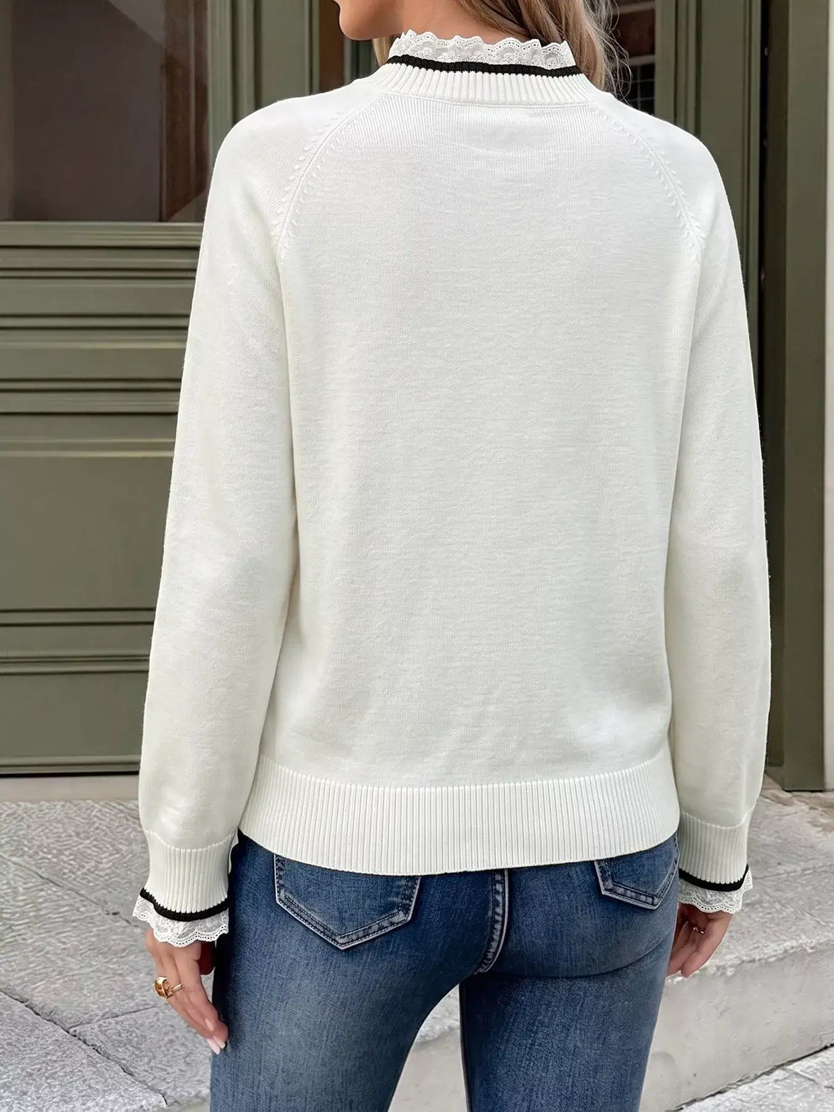Back view of a white Evie's Dreamland sweater with lace trim at the collar and cuffs, paired with blue jeans.