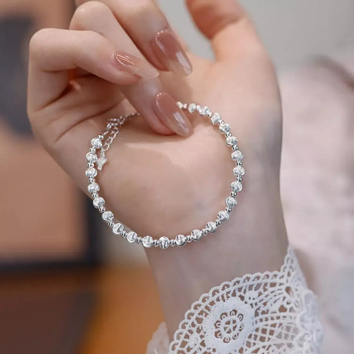 Trendsi 925 sterling silver beaded bracelet held in a hand over a white lace sleeve.