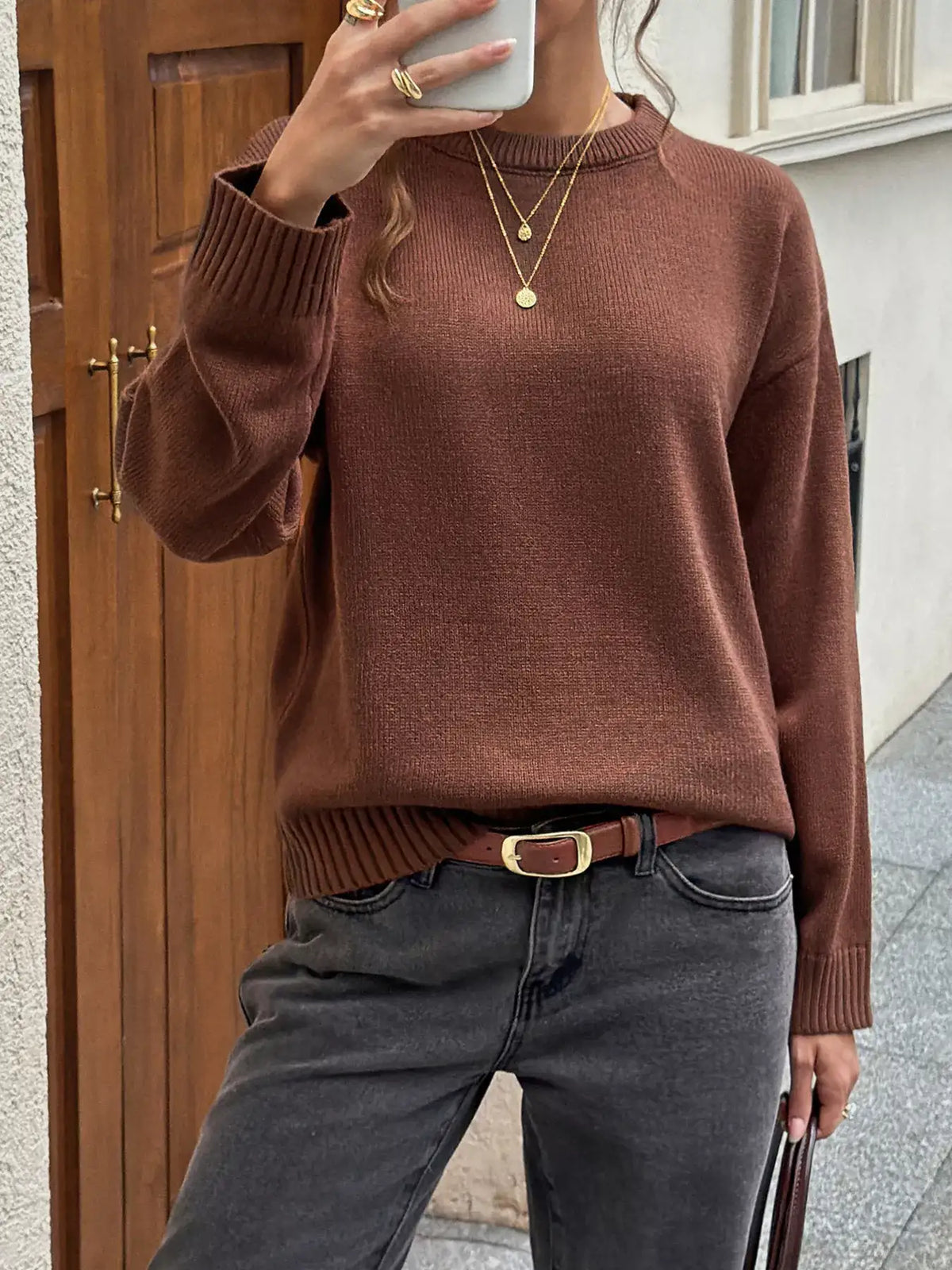 Woman wearing a brown crew neck ribbed hem sweater from Evie's Dreamland paired with grey jeans.