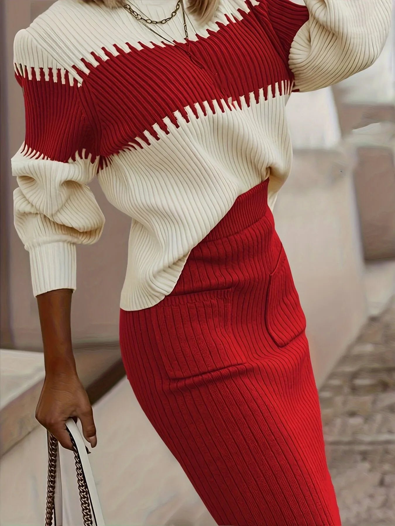Woman wearing a red and cream ribbed knit two-piece set with a coordinating handbag.
