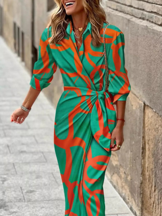 Smiling woman wearing green and orange patterned wrap dress walking on city sidewalk