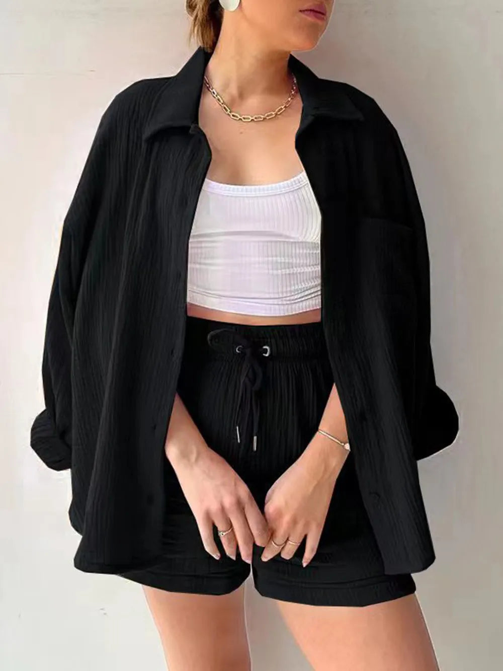 Woman wearing black button-up shirt, black drawstring shorts, and white crop top