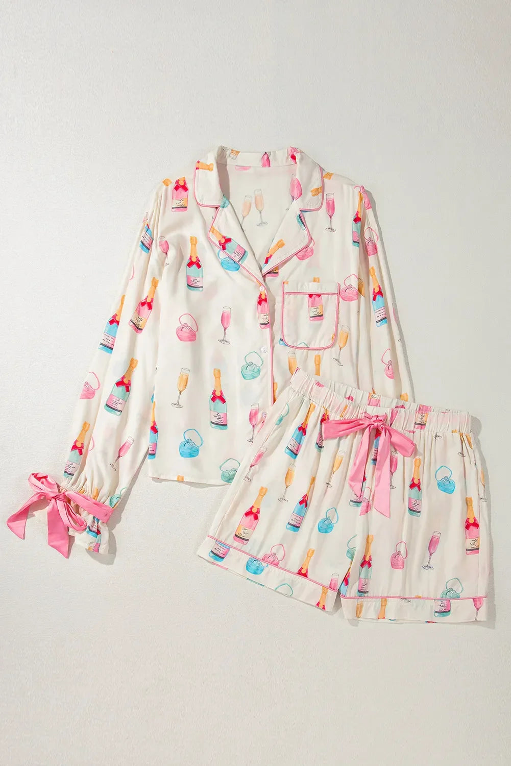 White long-sleeve and shorts pajama set with colorful champagne bottles, glasses, and pink bows