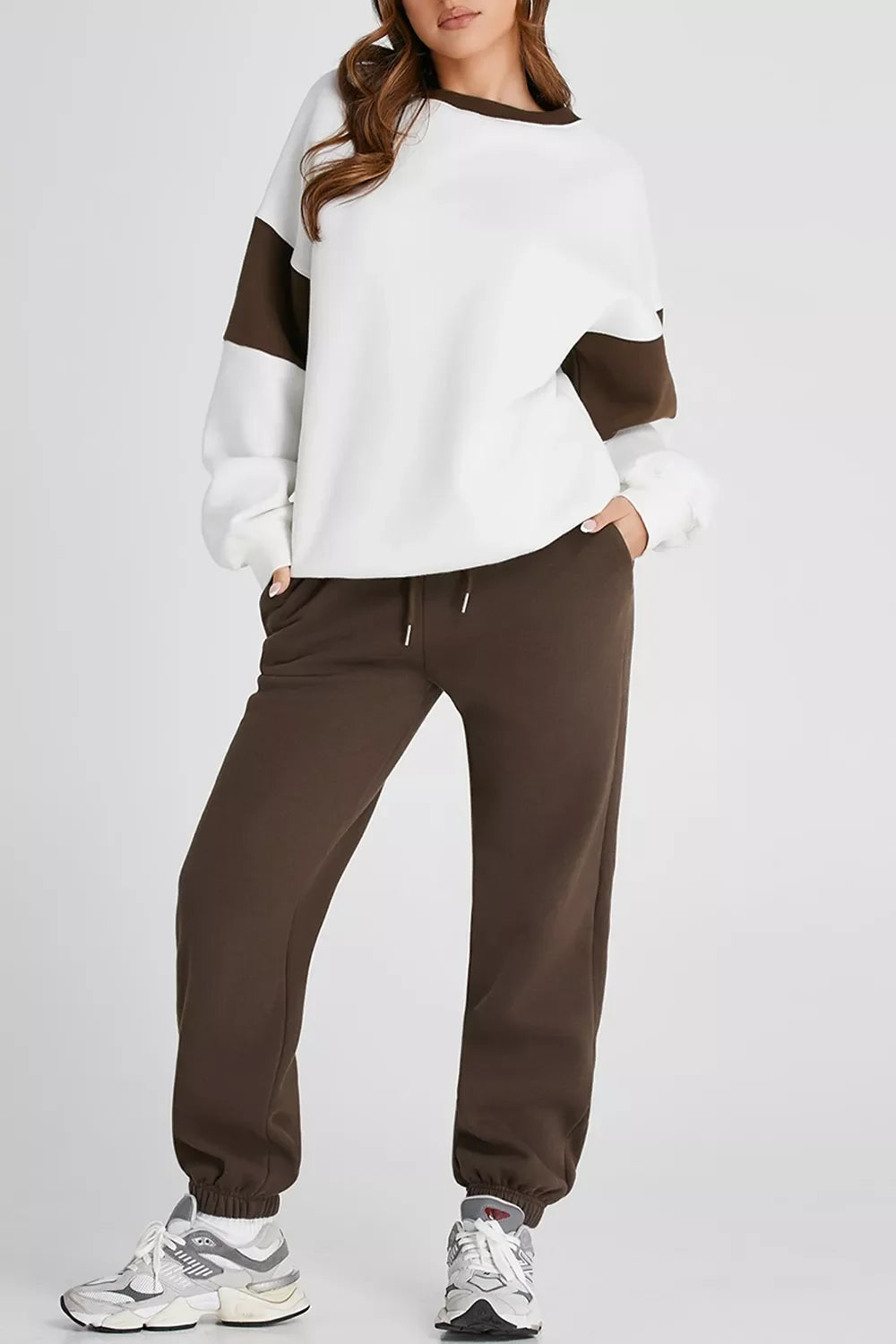 Woman wearing white and brown color-block sweatshirt with matching brown jogger pants and gray sneakers