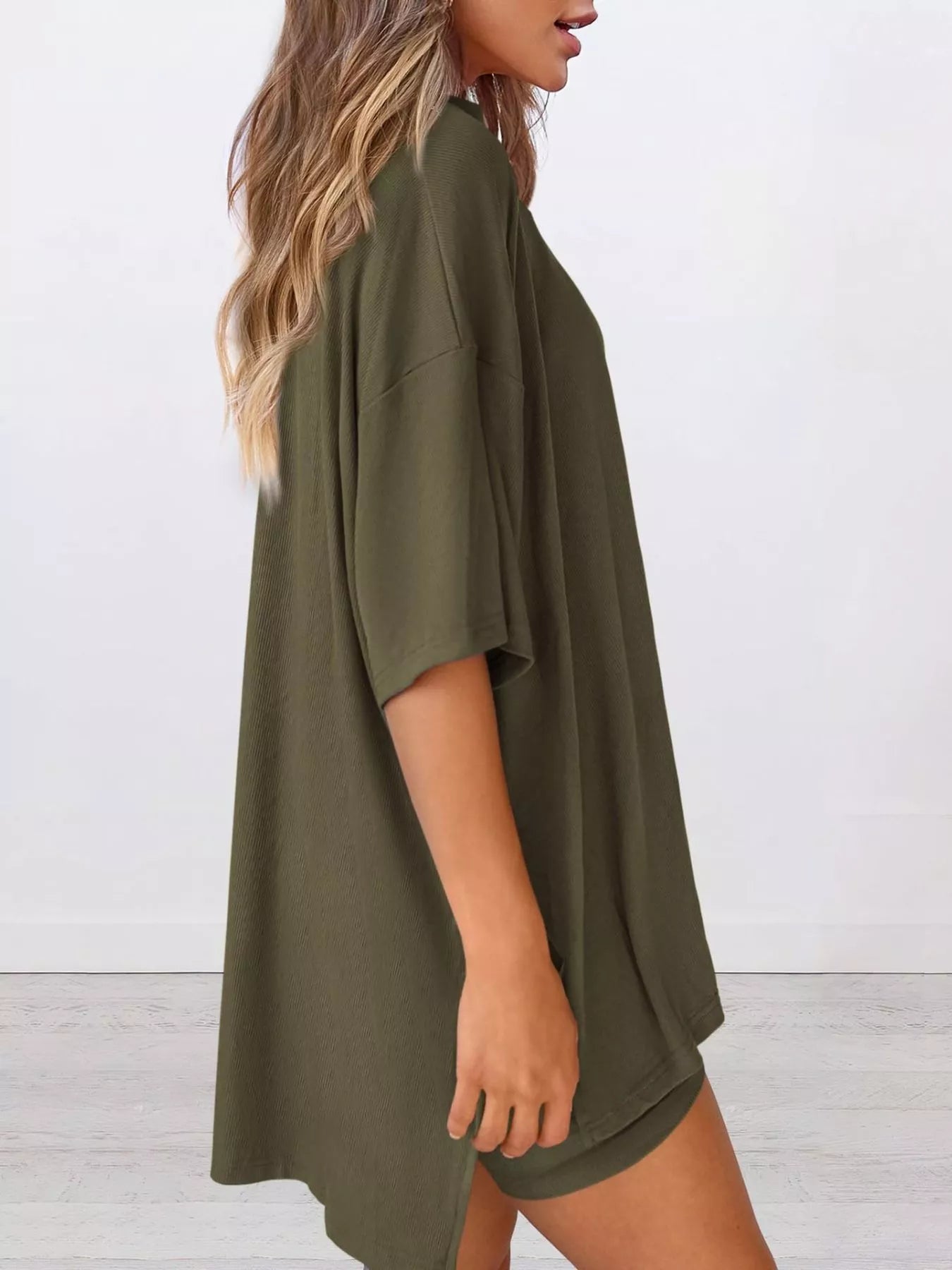 Woman wearing loose olive green oversized t-shirt dress in minimal indoor setting