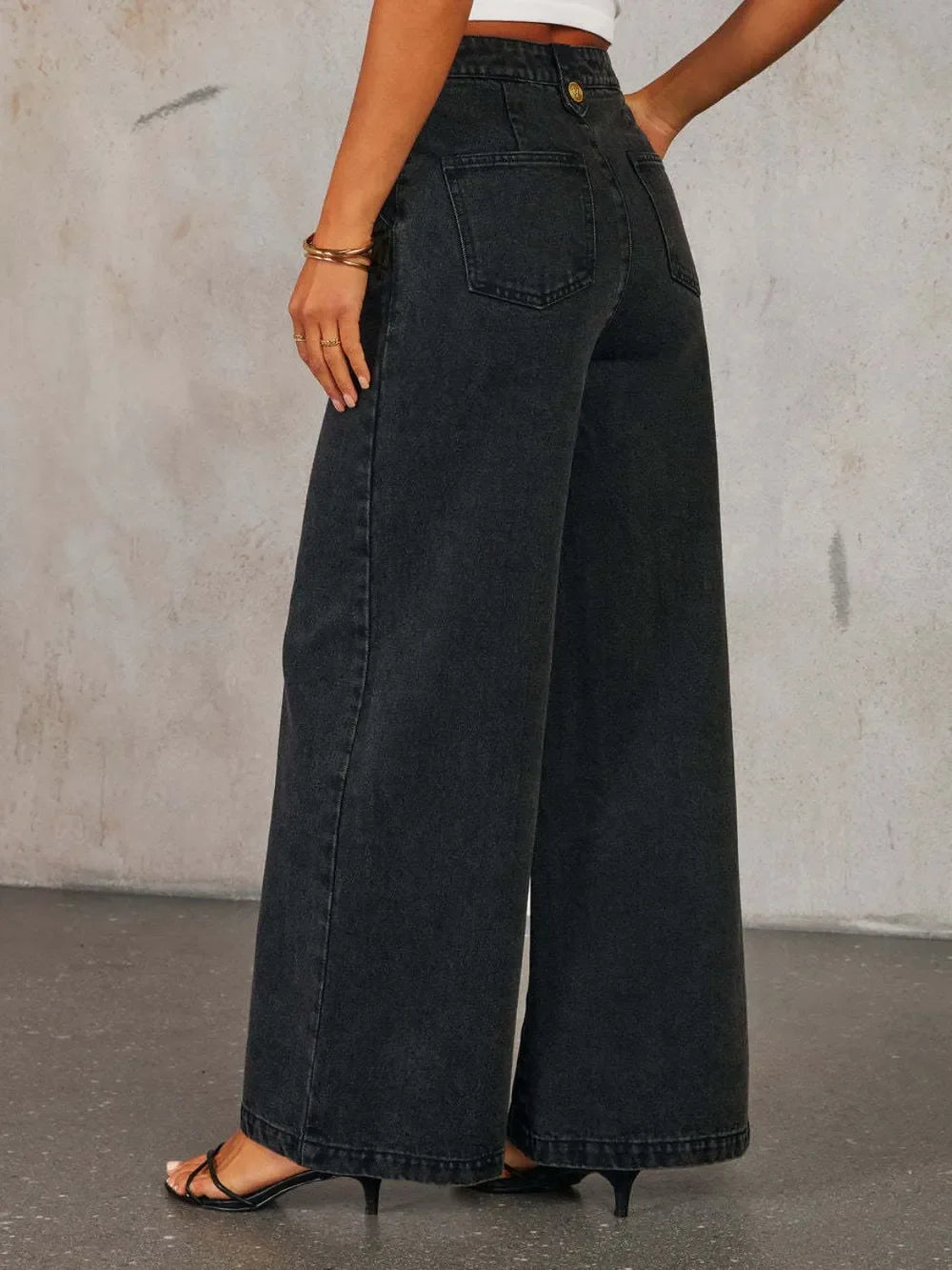 Woman wearing black wide leg high-waisted jeans and strappy heels, back view