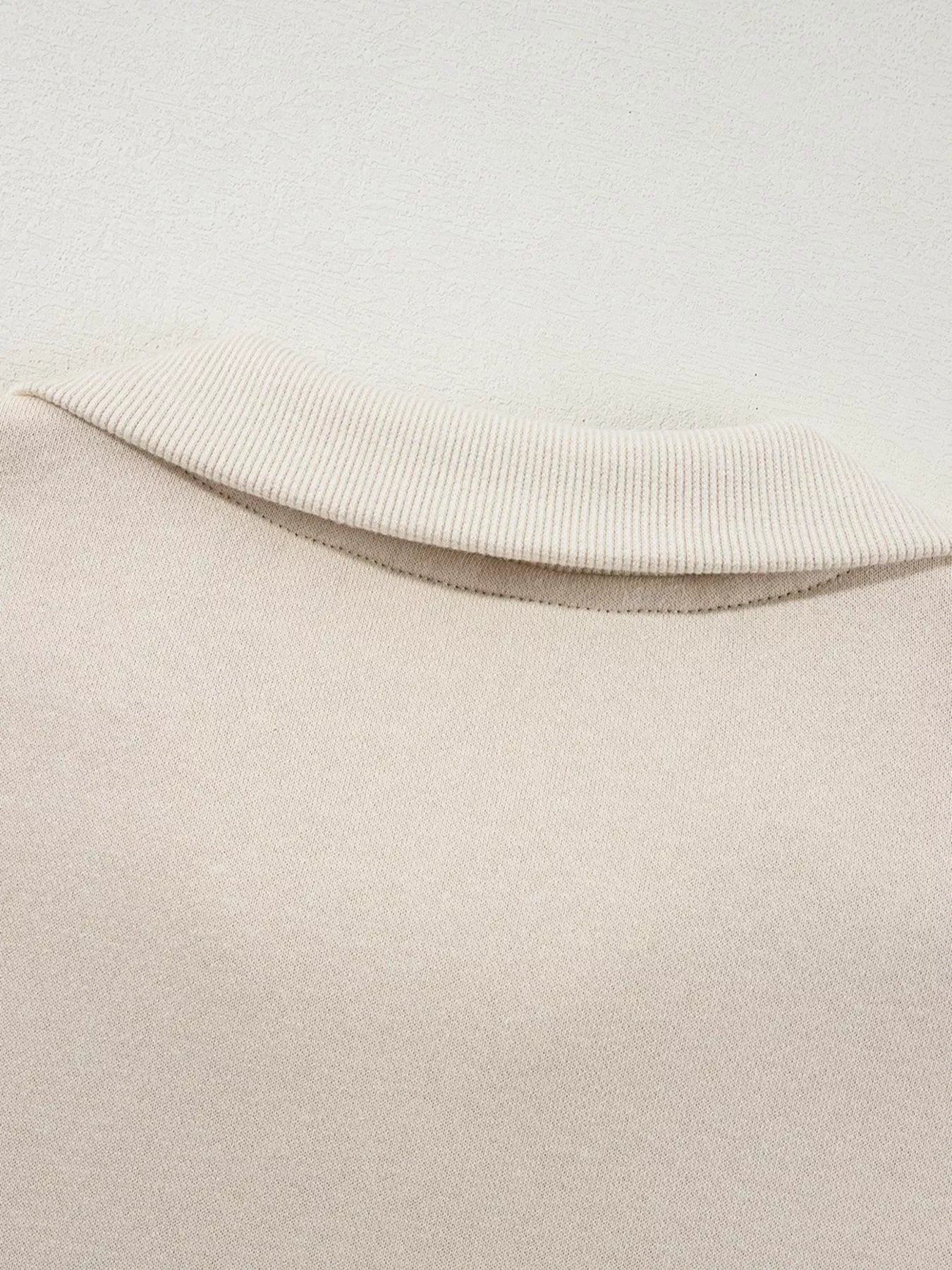 Close-up of beige ribbed collar on light-colored knit sweater fabric