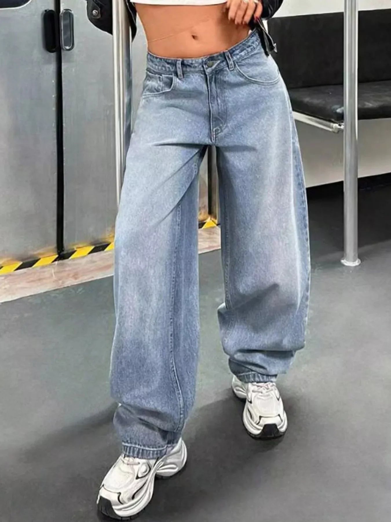 Woman wearing trendy baggy light wash jeans and white sneakers on public transport