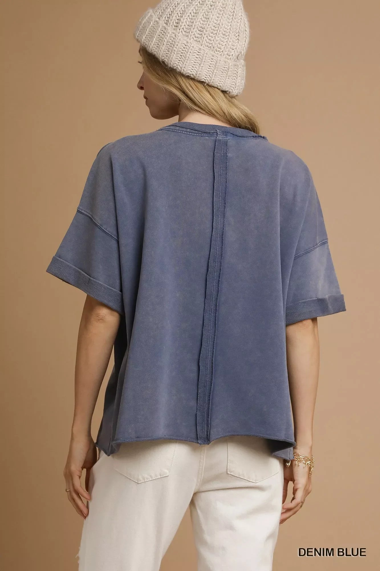 Woman wearing denim blue oversized short-sleeve top with exposed back seam and beige knit hat