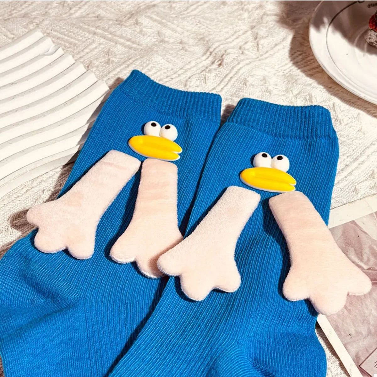 Blue socks with cartoon duck face and flipper designs on knitted fabric background