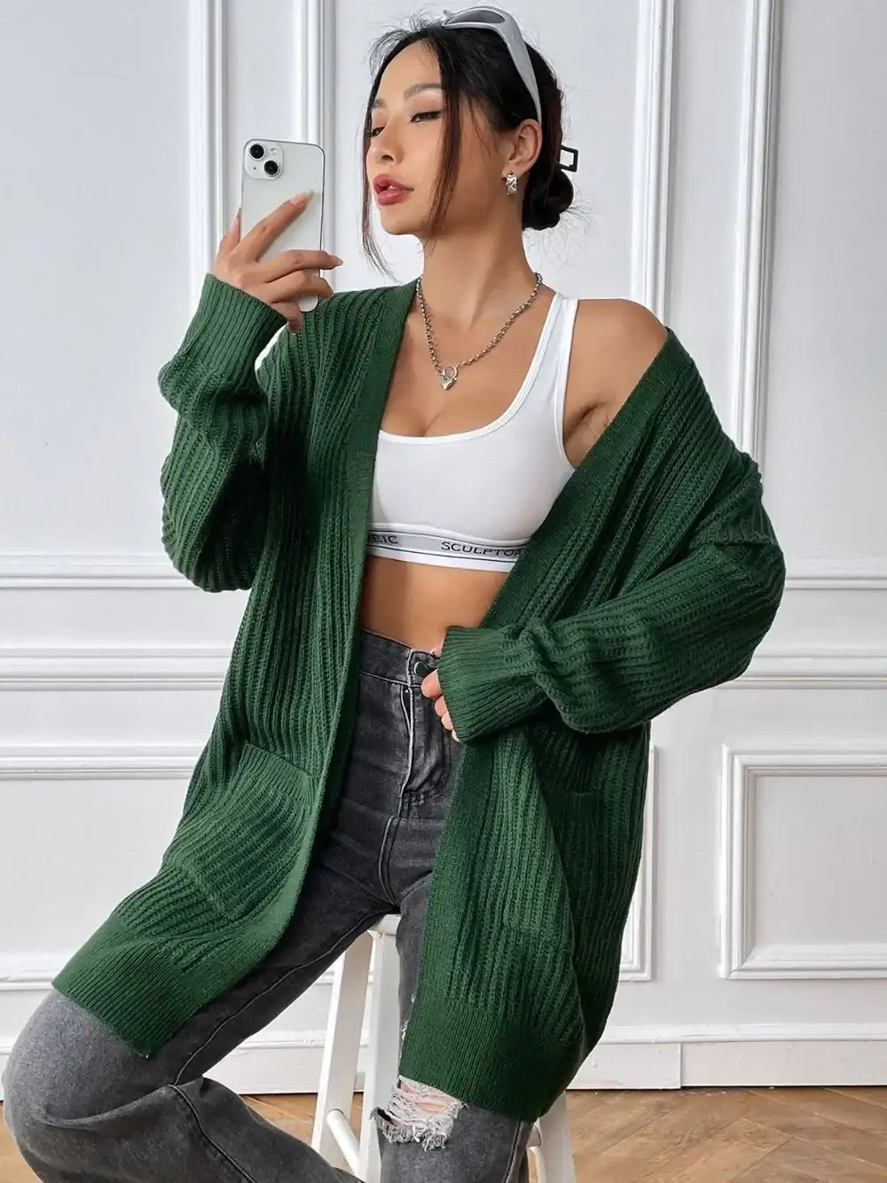 Woman wearing a long sleeve green open front knit cardigan by Evie's Dreamland over a white top.